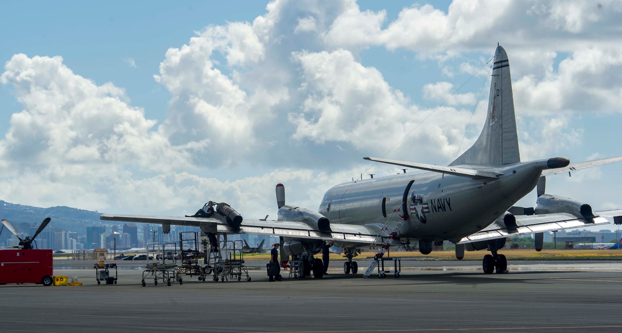 Sailors perform maintenance on a P-3 Orion maritime patrol aircraft on the Joint Base Pearl Harbor-Hickam, Hawaii, flightline Oct. 2, 2014. Navy and Marine Corps aircraft have temporarily relocated to JBPHH due to airfield construction at Marine Corps Air Station Kaneohe Bay. The aircraft commenced flying operations here Oct. 1. (U.S. Air Force photo by Tech. Sgt. Terri Paden)