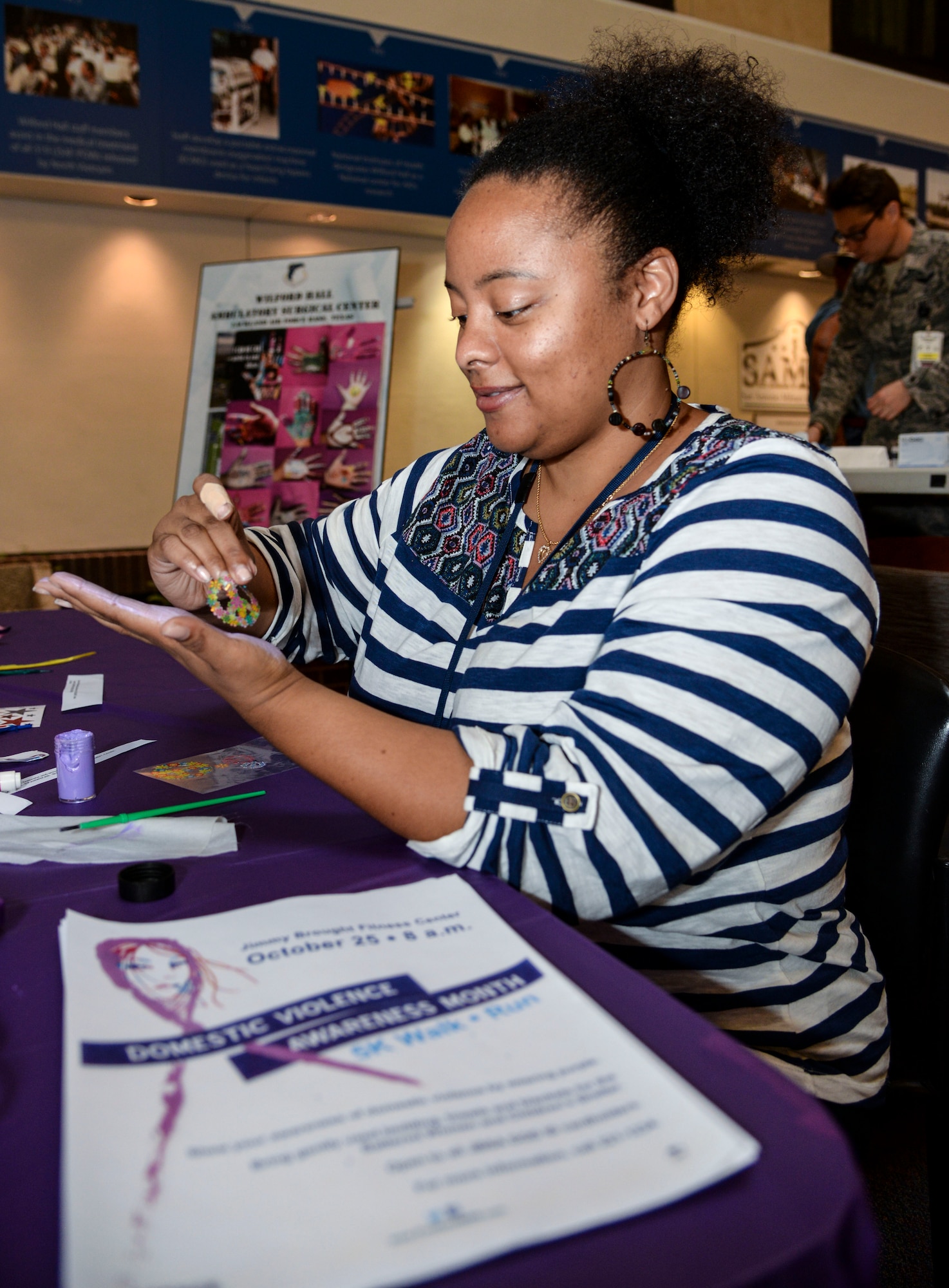 Chandra Peterson, 59th Medical Wing Family Advocacy manager, decorates her hand during the "I Can We Can" Domestic Violence Awareness Month event at Wilford Hall Ambulatory Surgical Center, Joint Base San Antonio-Lackland, Texas, Oct. 3, 2014. Supporters painted and decorated their hand and wrote what they are going to do to help stop domestic violence. (U.S. Air Force photo/Senior Airman Michael Ellis)