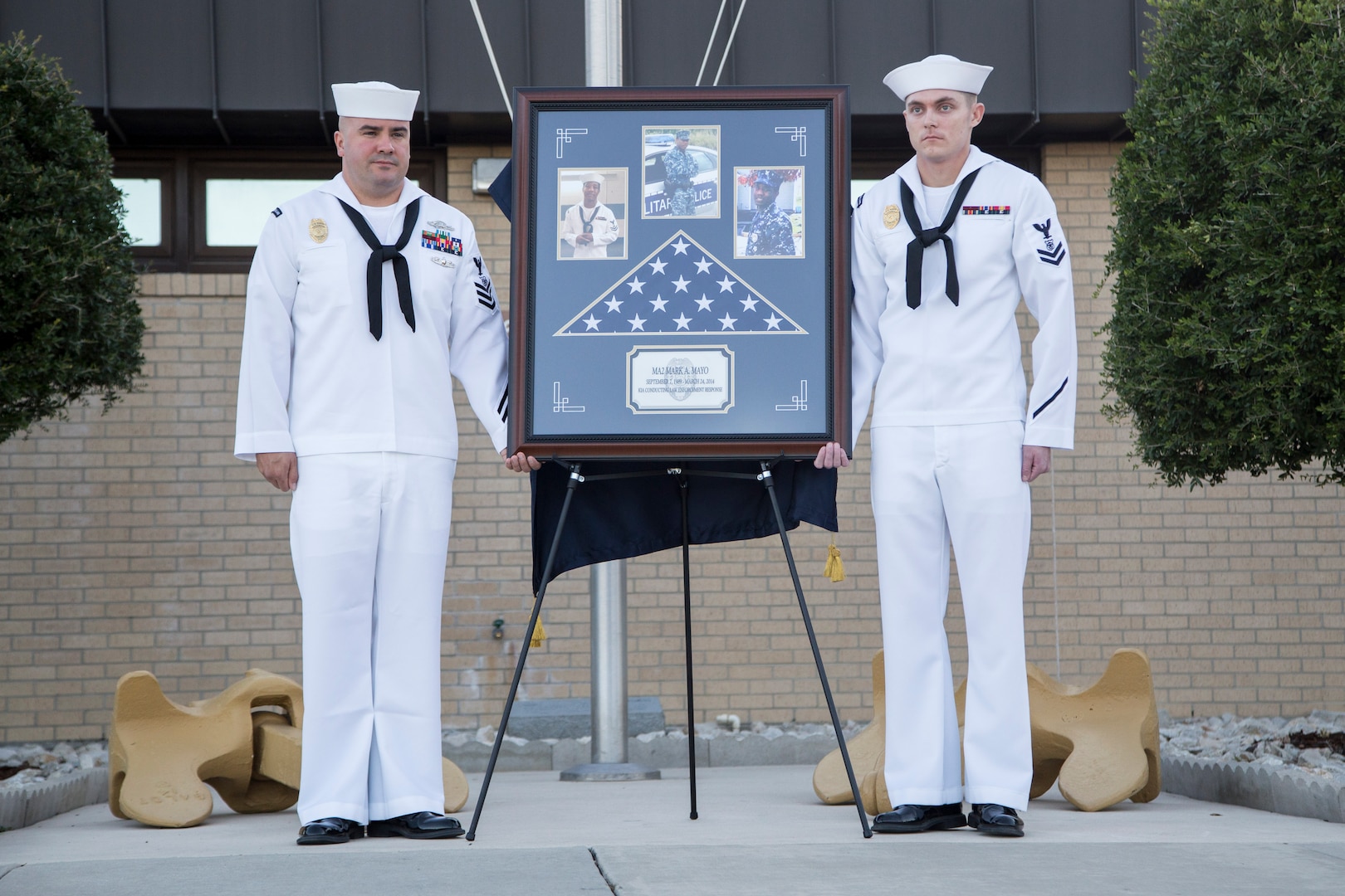 Petty officers unveil a memorial honoring Master-at-Arms 2nd Class Mark Mayo Oct. 3, 2014 at the Naval Technical Training Center Lackland. Mayo died in the line of duty in March 2014 while stationed aboard the USS Mahan (DDG-72) at Norfolk Naval Station, Va.. For his actions that day, Mayo was posthumously awarded the Navy Marine Corps Medal, the second-highest non-combat decoration awarded for heroism. (U.S. Air Force photo by Joshua Rodriguez/Released)