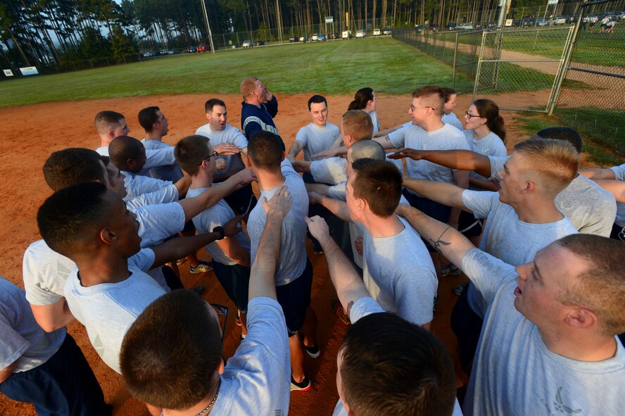 U.S. Air Force Airmen assigned to the 20th Communications Squadron, huddle together for a squadron chant after playing a game of kickball at Shaw Air Force Base, S.C., Oct. 3, 2014. Approximately 30 Airmen participated in the game as part of their weekly physical training to enhance squadron morale and camaraderie. (U.S. Air Force photo by Airman 1st Class Jensen Stidham/Released)