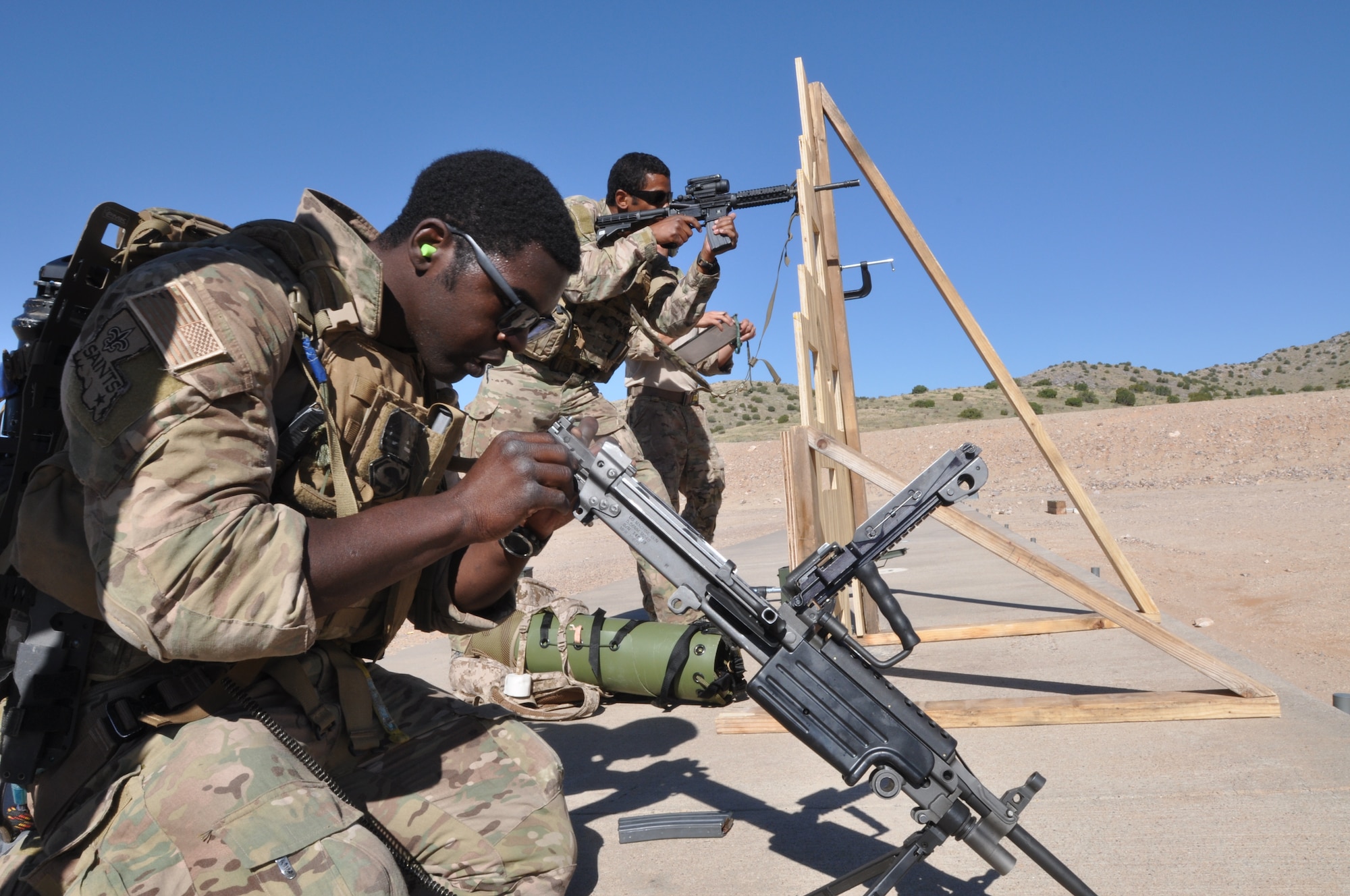 A pararescuman shoots his rifle downrange while his teammates assembles another rifle as part of a stress-shooting and patient-care exercise during the 2014 Guardian Angel Rodeo, Kirtland Air Force Base, New Mexico, September 25, 2014. The rodeo, or competition, was a week-long event that tested the PJs on land navigation skills, high-angel rope rescues, survival techniques, medical skills, weapons operations and overall physical endurance. (U.S. Air Force photo/ Tech. Sgt. Katie Spencer)