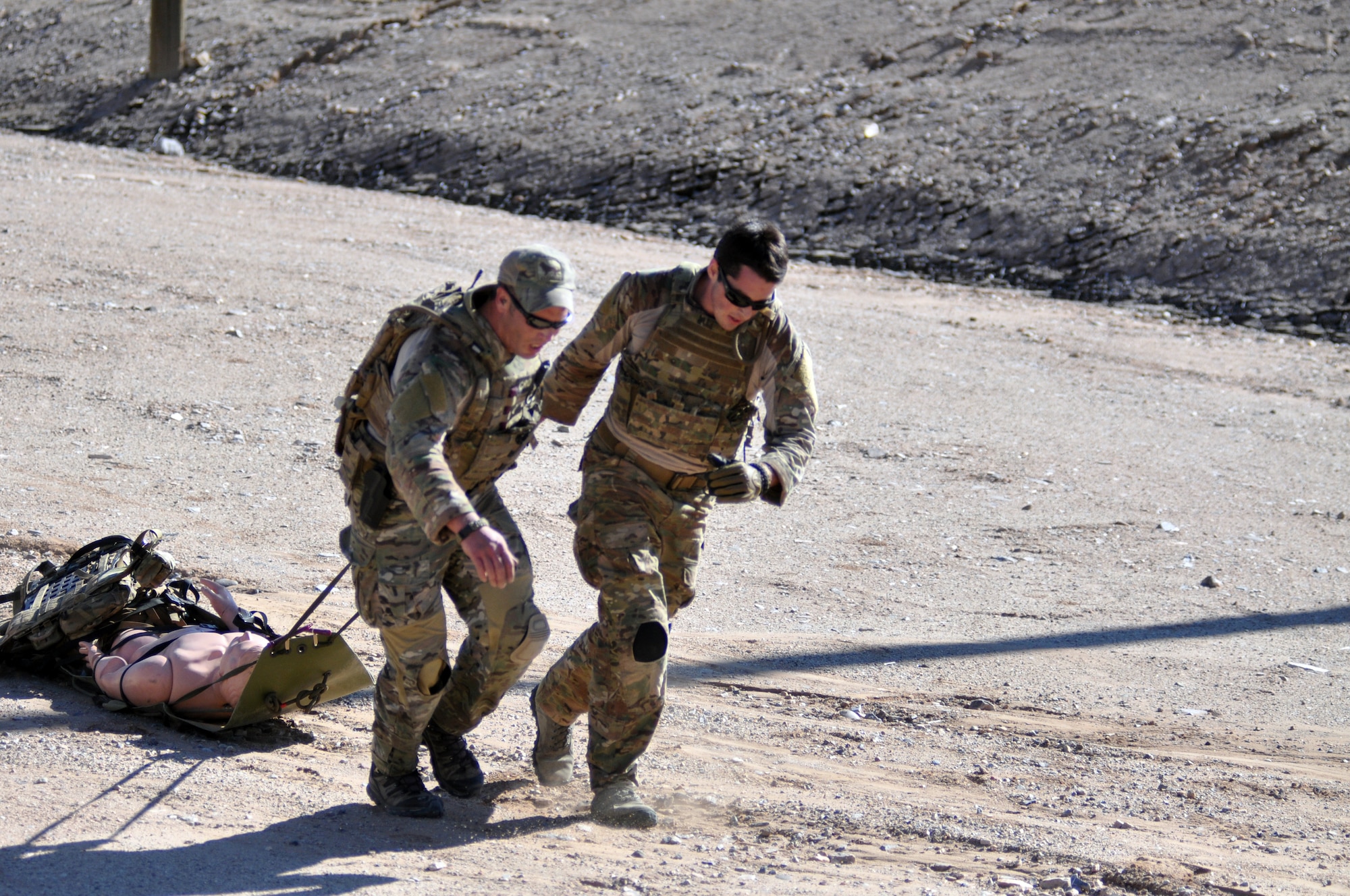 Two pararescuemen drag a patient to safety as part of a stress-shooting and patient-care exercise during the 2014 Guardian Angel Rodeo, Kirtland Air Force Base, New Mexico, September 25, 2014. The rodeo, or competition, was a week-long event that tested the PJs on land navigation skills, high-angel rope rescues, survival techniques, medical skills, weapons operations and overall physical endurance. (U.S. Air Force photo/ Tech. Sgt. Katie Spencer)