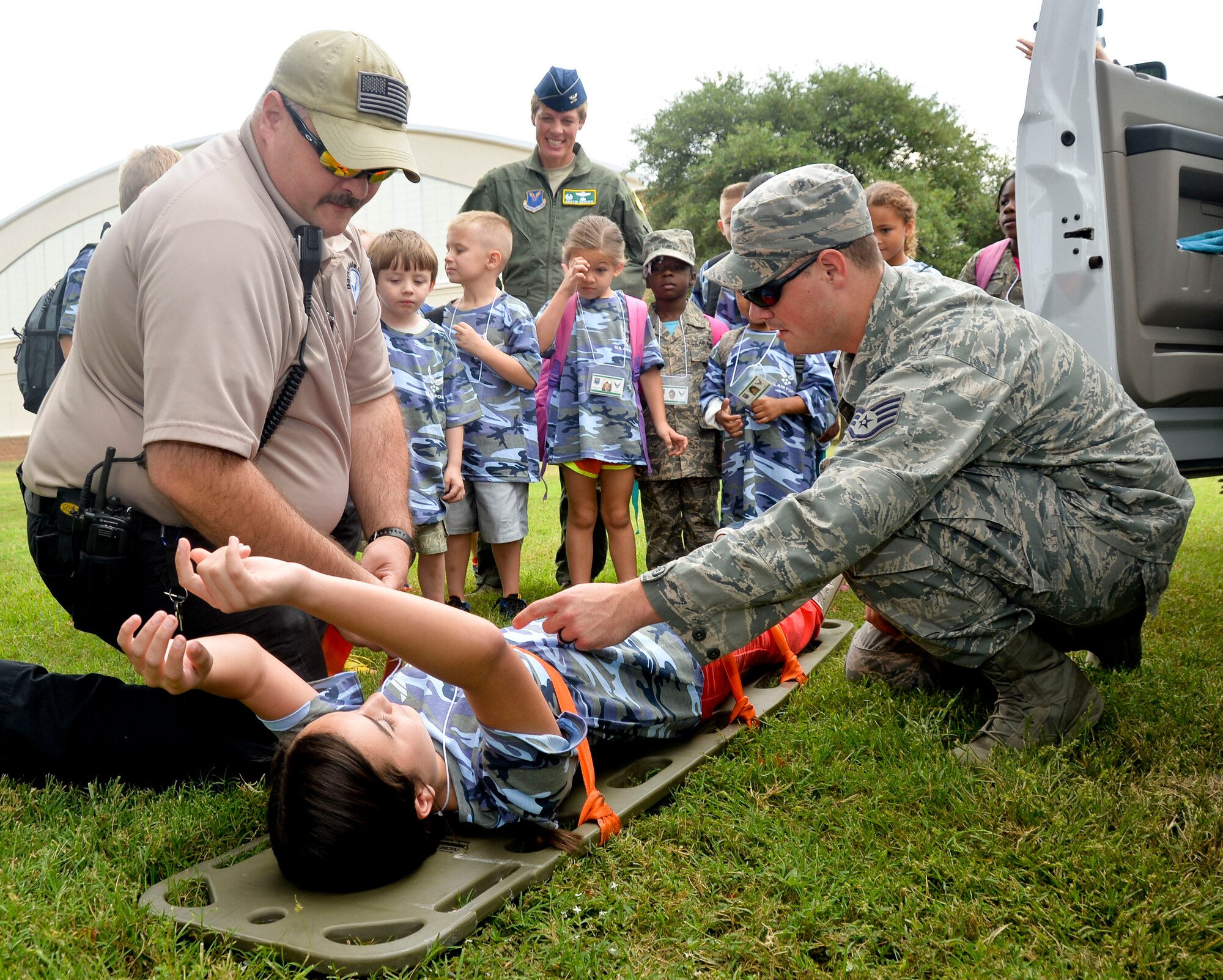 Staff Sgt. Matt McCloud, 2nd Medical Operations Squadron medic, and Robert Cline, 2nd MDOS paramedic, demonstrate the use of a stretcher on Barksdale Air Force Base, La., Sept. 27, 2014. Operation Hero aims to demonstrate to children the tools available to keep their parents safe during deployments. (U.S. Air Force photo/Airman 1st Class Mozer O. Da Cunha)