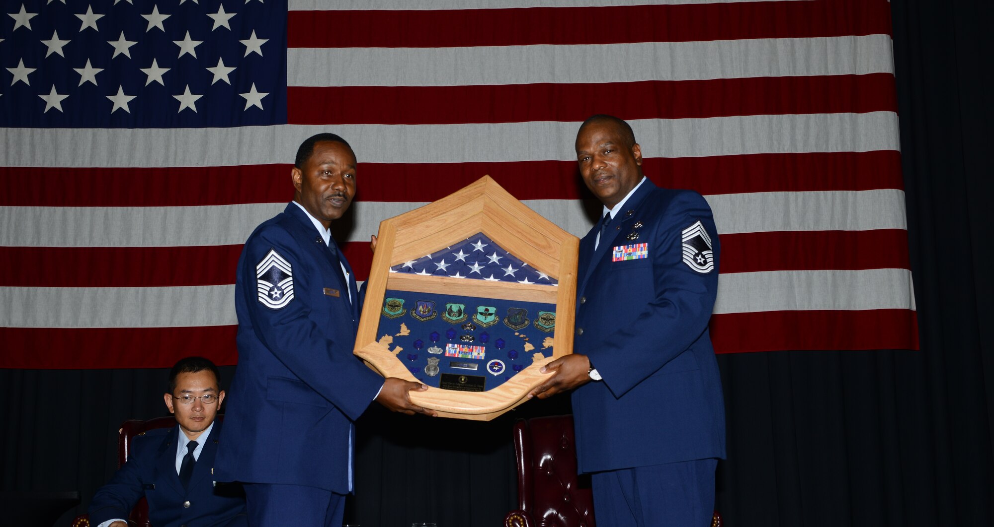Chief Master Sgt. Lee Green, 80 Aerial Port Squadron, presents his brother Chief Master Sgt. Norman Green, 22nd Civil Engineer Squadron individual mobile augmentee, with a shadowbox at Norman's retirement ceremony July 25, 2014, at McConnell AIr Force Base, Kan. Only one percent of Airmen who enlist ever make it to the rank of chief, yet these two brothers accomplished this task. (U.S. Air Force photo by Senior Airman Trevor Rhynes/Released)