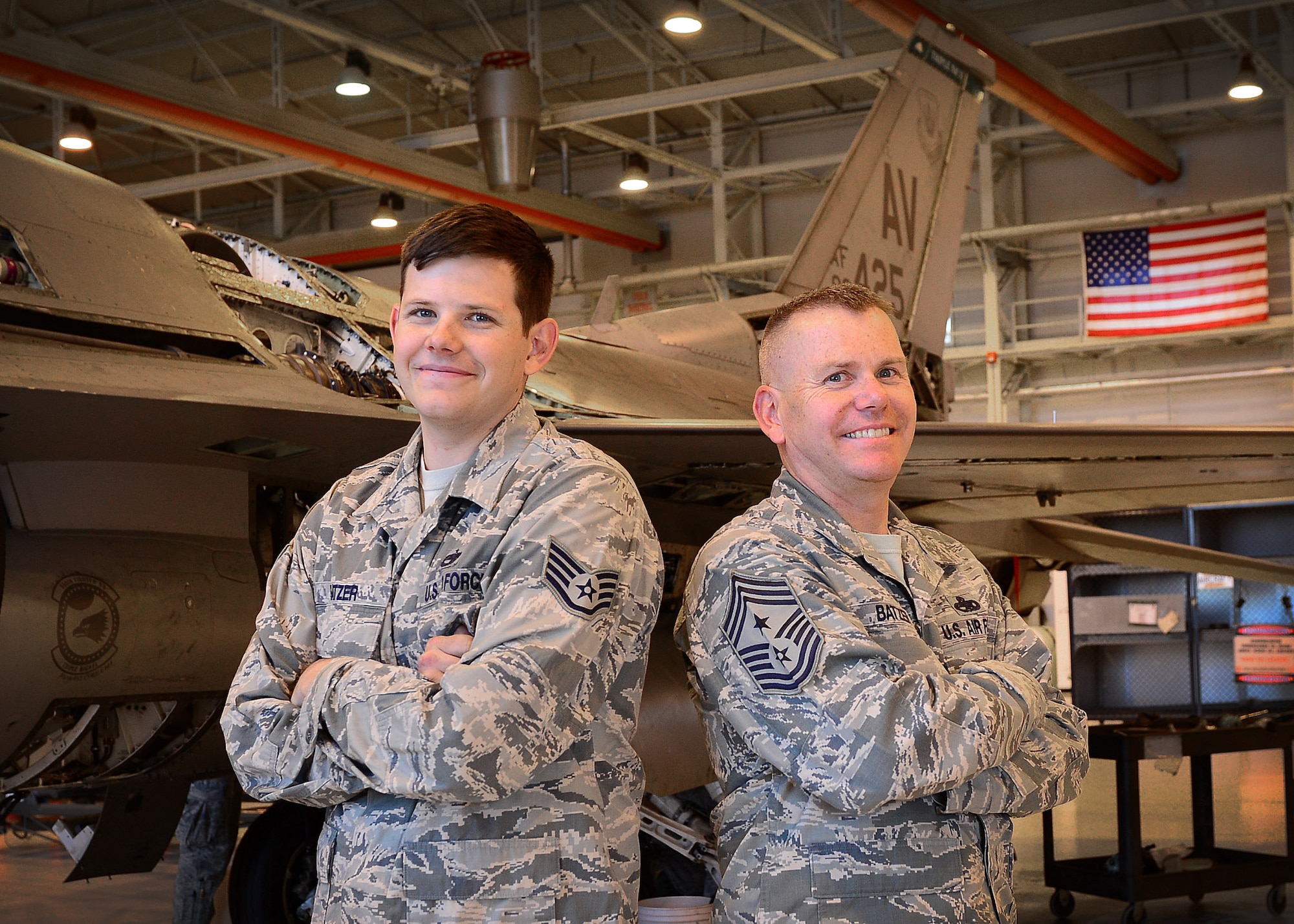 Staff Sgt. Tom Batzer stands with his father, Chief Master Sgt. Mark Batzer, next to an F-16 Fighting Falcon, Sept. 25, 2014, at Aviano Air Base, Italy. As members of Team Aviano, Chief Batzer will soon retire as the 31st Fighter Wing command chief, while his son continues serving as a 31st Maintenance Squadron aircraft maintainer. (U.S. Air Force photo/Senior Airman Matthew Lotz)