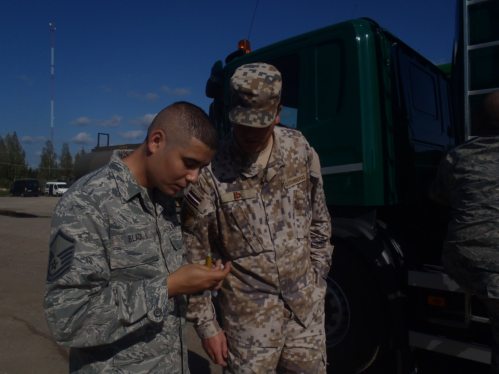 Master Sgt. Albert Black, 435th Contingency Response Group air advisor, discusses water detection in fuels with a Latvian navy lieutenant commander at Lielvarde Air Base, Latvia.
 The 435th Air Ground Operations Wing’s Air Advisor Branch executed five missions at once, the most it has ever done in one week, Sept. 15 to 19 in three NATO countries.
