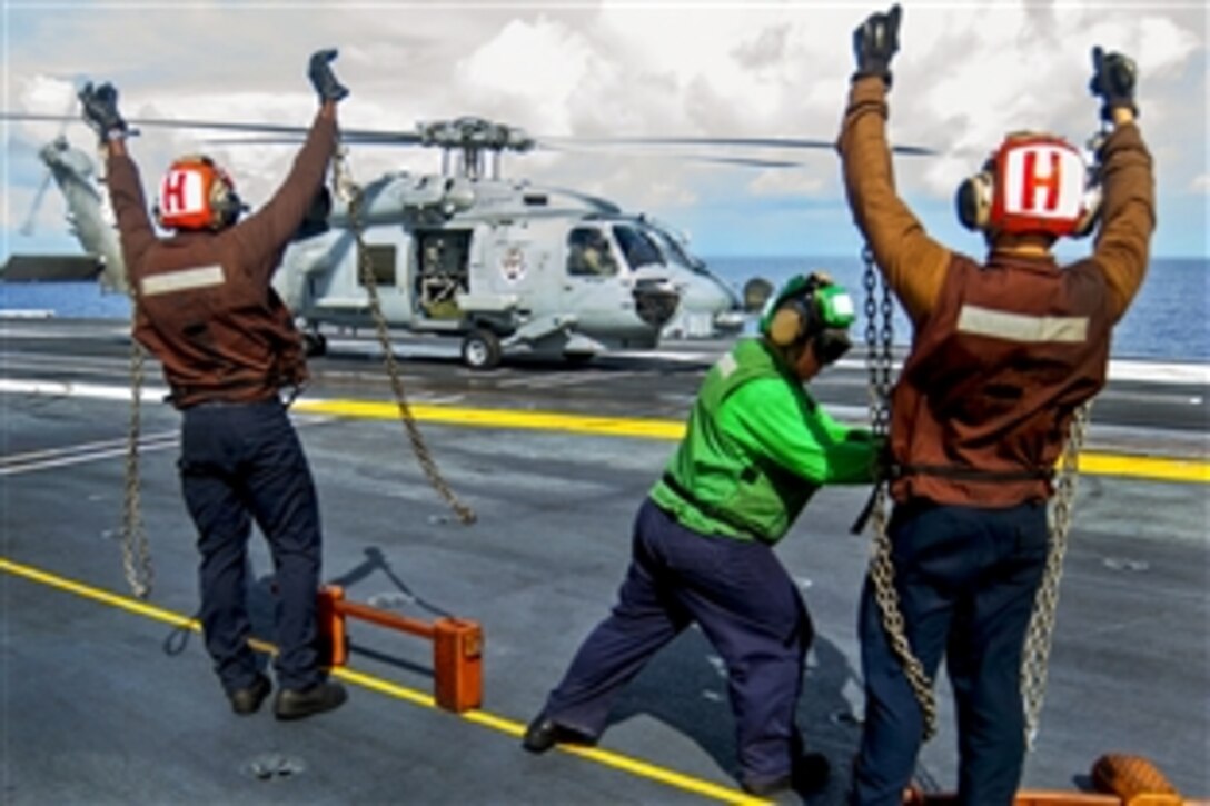 U.S. sailors show that chocks and chains have been removed from an MH-60R Seahawk helicopter before it lifts off the flight deck of the aircraft carrier USS Carl Vinson in the Pacific Ocean, Sept. 22, 2014. The sailors are assigned to Maritime Strike Squadron 73. The Vinson and its embarked Carrier Air Wing 17 are deployed to the 7th Fleet area of operations supporting Valiant Shield.