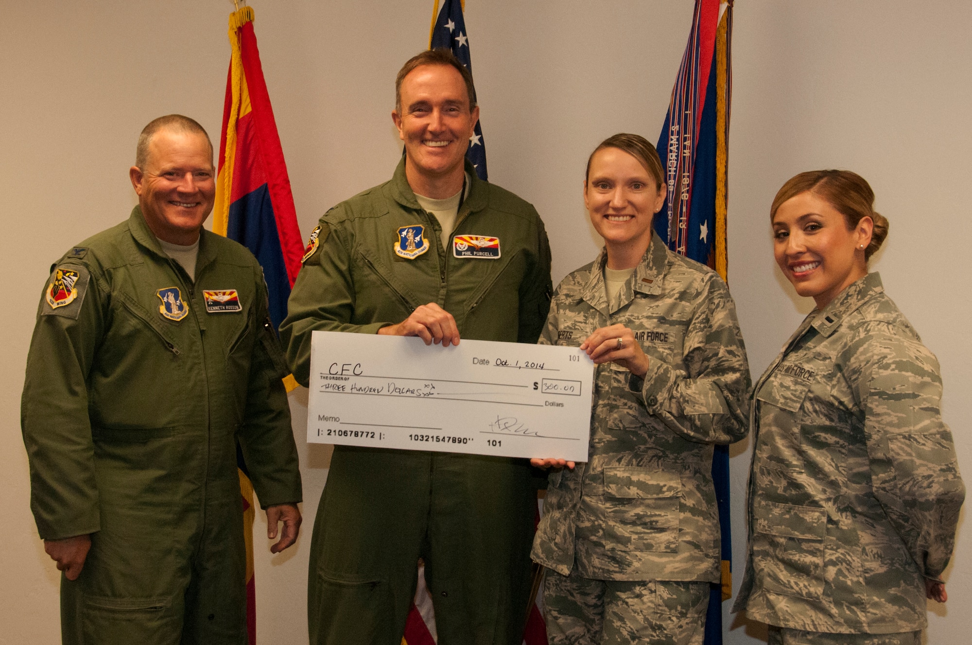 Col. Phil Purcell, 162nd Wing commander, presents a $300 check to 2014 162nd Wing Combined Federal Campaign coordinators, 1st Lt. Erika Palomino and 2nd Lt. Lacey Roberts. Not to be outdone by the “boss,” Vice Wing Commander Kenneth L. Rosson (left) matched Purcell’s act of benevolence. (U.S. Air National Guard photo by 2nd Lt. Lacey Roberts)