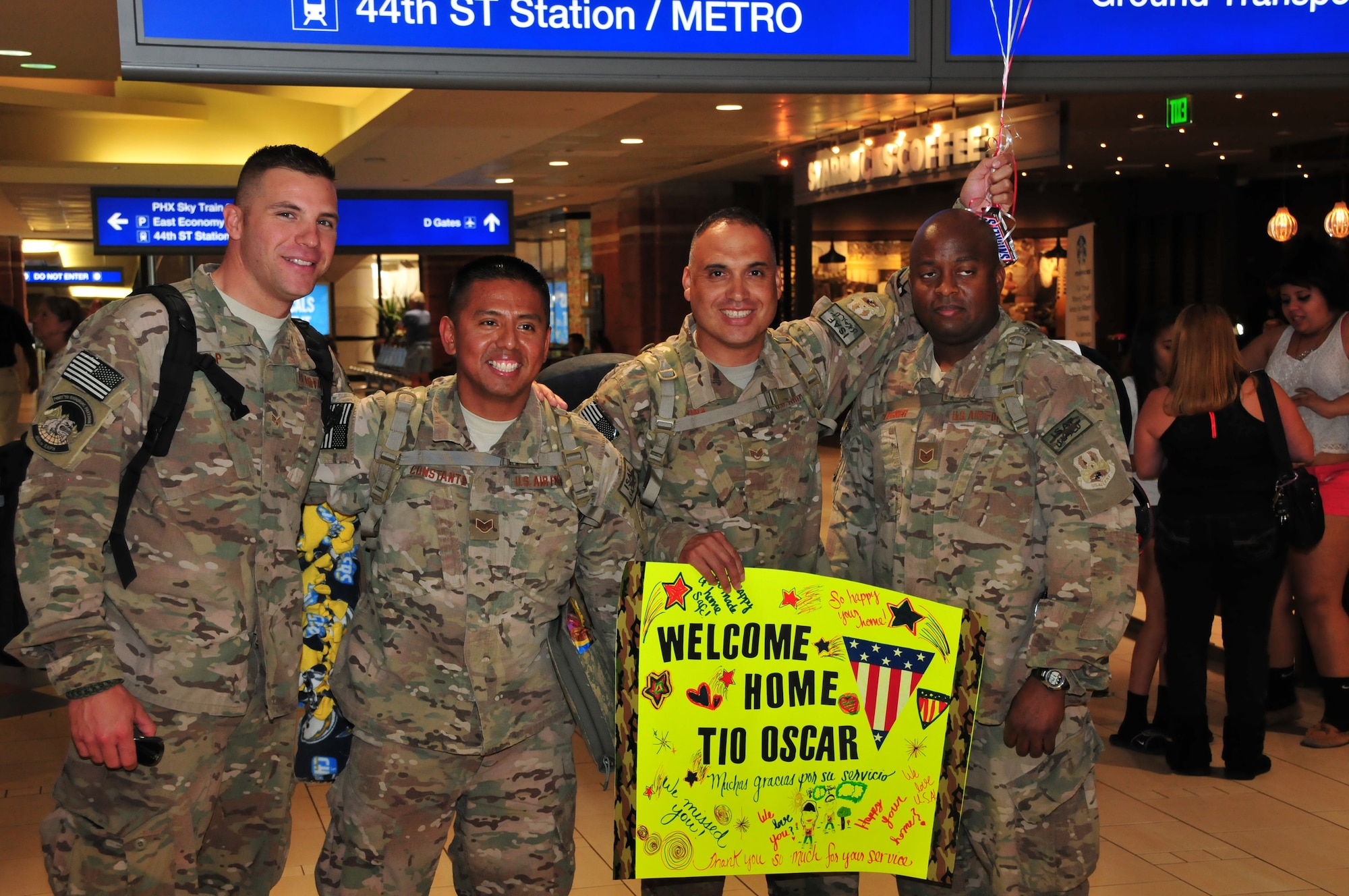 Senior Airman Ryan Culp, Staff Sgt. Rene Constante, Staff Sgt. Oscar Serna and Technical Sgt. Jeon Turner of the 161st Air Refueling Wing Logistics Readiness Squadron are welcomed back to Arizona at the Phoenix Sky Harbor International Airport after their recent deployment, Oct. 3, 2014. Fourteen Airmen from the 161st ARW Aerial Port spent seven months in Afghanistan in support of Operation Enduring Freedom. (U. S. Air National Guard photo by Master Sgt. Kelly M. Deitloff/released)