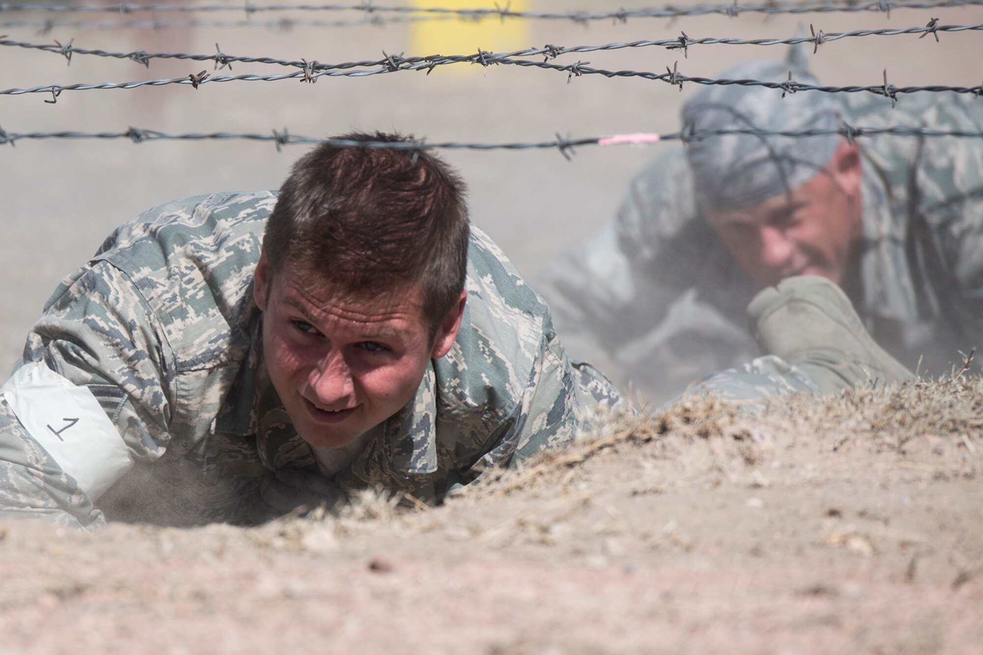 U.S. Air Force Staff Sgts. Johnathan Maupin and Randy Patrick, 307th Security Forces Squadron, crawl their way underneath strands of barbed wire during the Global Strike Challenge Mental and Physical competition, Sept. 25, 2014, Camp Guernsey, Wyo. The Global Strike Challenge is the world's premier bomber, Intercontinental Ballistic Missile, helicopter operations and security forces competition with units from Air Force Global Strike Command, Air Combat Command, Air Force Reserve Command and the Air National Guard. (U.S. Air Force photo by Master Sgt. Greg Steele/Released)