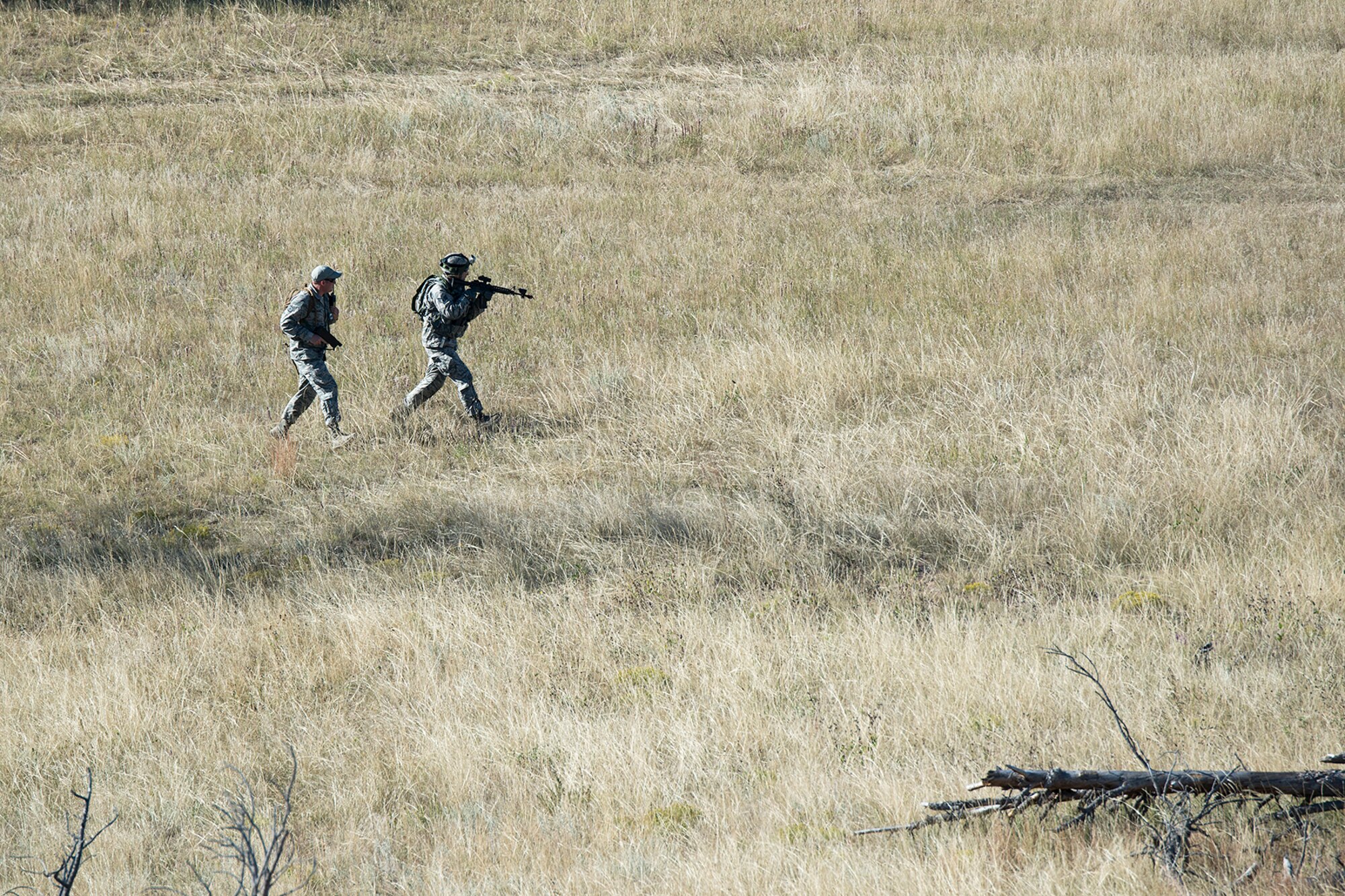 A member of the 307th Security Forces Squadron is followed by an observer as he maneuvers through an open field during the Global Strike Challenge Tactical competition, Sept. 23, 2014, Camp Guernsey, Wyo. The Global Strike Challenge is the world's premier bomber, Intercontinental Ballistic Missile, helicopter operations and security forces competition with units from Air Force Global Strike Command, Air Combat Command, Air Force Reserve Command and the Air National Guard. (U.S. Air Force photo by Master Sgt. Greg Steele/Released)