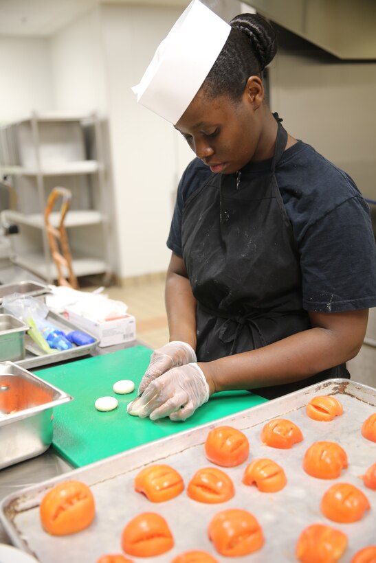 Lance Cpl. Bianca Sanders cuts slices of baby mozzarella cheese for a caprese salad during the 2014 Chef of the Year competition at Marine Corps Air Station Cherry Point, N.C., Oct. 2, 2014. Sanders was the first-place winner in the competition, cooking an “Alice in Wonderland” themed meal. Sanders is a native of Fayetteville, N.C., and a food service specialist with Marine Wing Support Squadron 271.