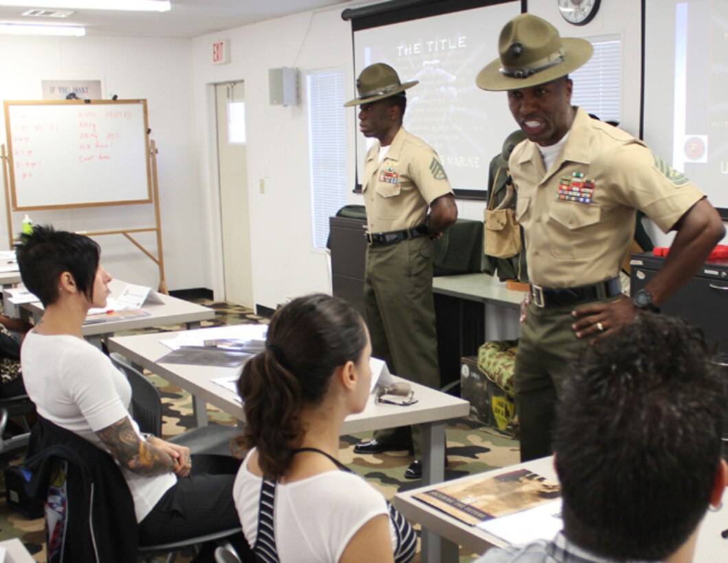 Gunnery Sgt. Nicholas Underwood, senior drill instructor at Officer Candidates School aboard Marine Corps Base Quantico, shouts orders to a group of civilians who are attending a Marine Corps acculturation class July 30, in one of the trailers outside the National Museum of the Marine Corps.  Underwood and Staff Sgt. Luc Cadet, who is standing in the rear at parade rest, assisted with acclimating civilian employees to a Marine Corps environment. 