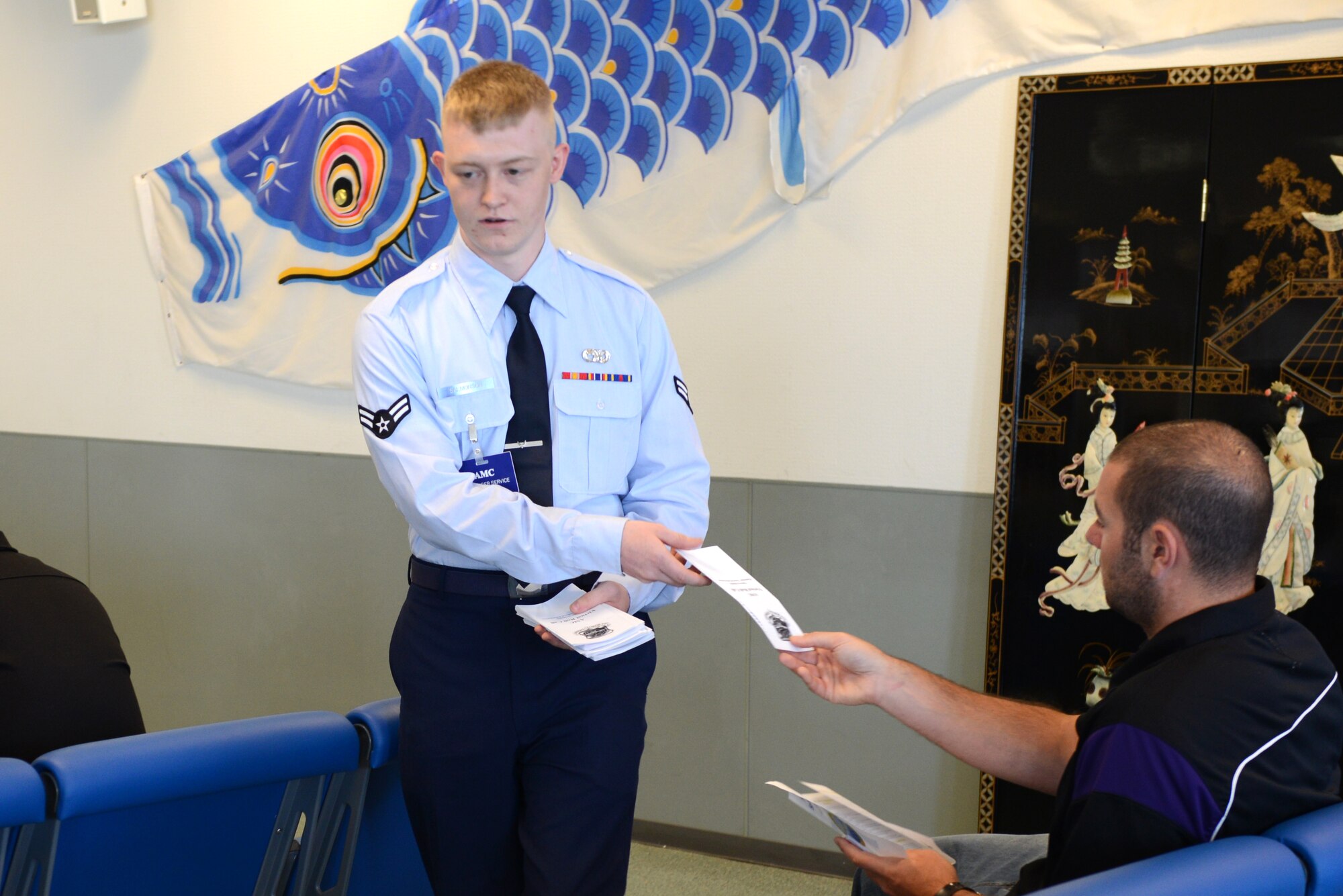 Airman 1st Class Tanner Salmonson, 730th Air Mobility Squadron passenger service agent, hands out flyers at the 730 AMS open house at Yokota Air Base, Japan, Sept. 29, 2014. The flyers contained information on 730 AMS programs and services. (U.S. Air Force photo by Airman 1st Class David C. Danford/Released)