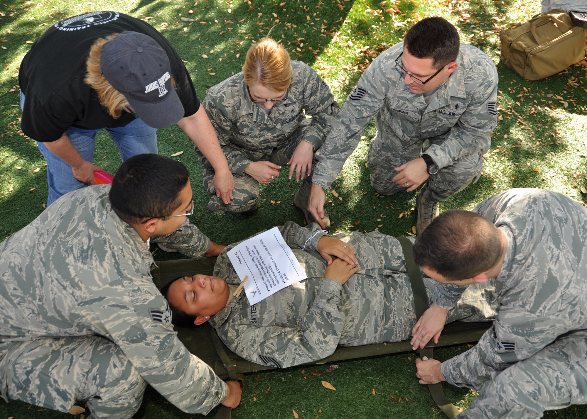 A team of 940th Aerospace Medicine Squadron members arrange Tech. Sgt. Joyce Satterfield, an optometry technician and simulated patient exhibiting blood loss, on a litter during a Mass Casualty Exercise, Oct. 5, 2014, Beale Air Force Base, Calif. Barbara Boyer, a retired lieutenant colonel and former 940th AMDS chief nurse, instructs the litter team on how to properly arrange the litter straps so as not to further injure the 'patient.' Boyer, along with other retired medical personnel, served as evaluators and patients to provide their expertise during the exercise. (U.S. Air Force photo by Tech. Sgt. Heather Skinkle/Released)