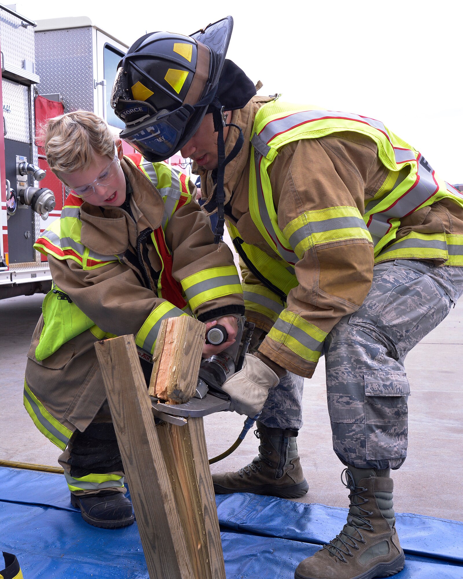 Benny Remmer, 7, the Academy's latest Cadet for a Day, works with Senior
Airman Sean Kaufmann, a 10th Civil Engineer Squadron firefighter here Oct.
3, 2014, to cut through a piece of wood with a cutter, a tool firefighters use to
slice through the metal of a car to aid the victim of a vehicle accident.
(U.S. Air Force photo/Jason Gutierrez)
