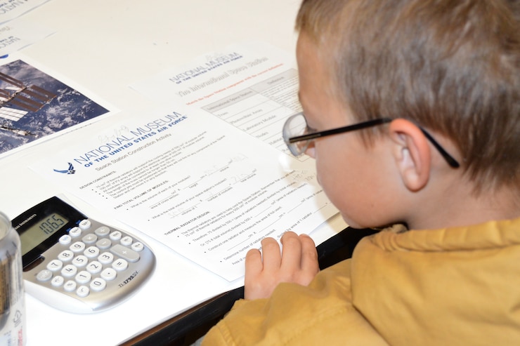 Picture of a boy working on a paper with a calculator