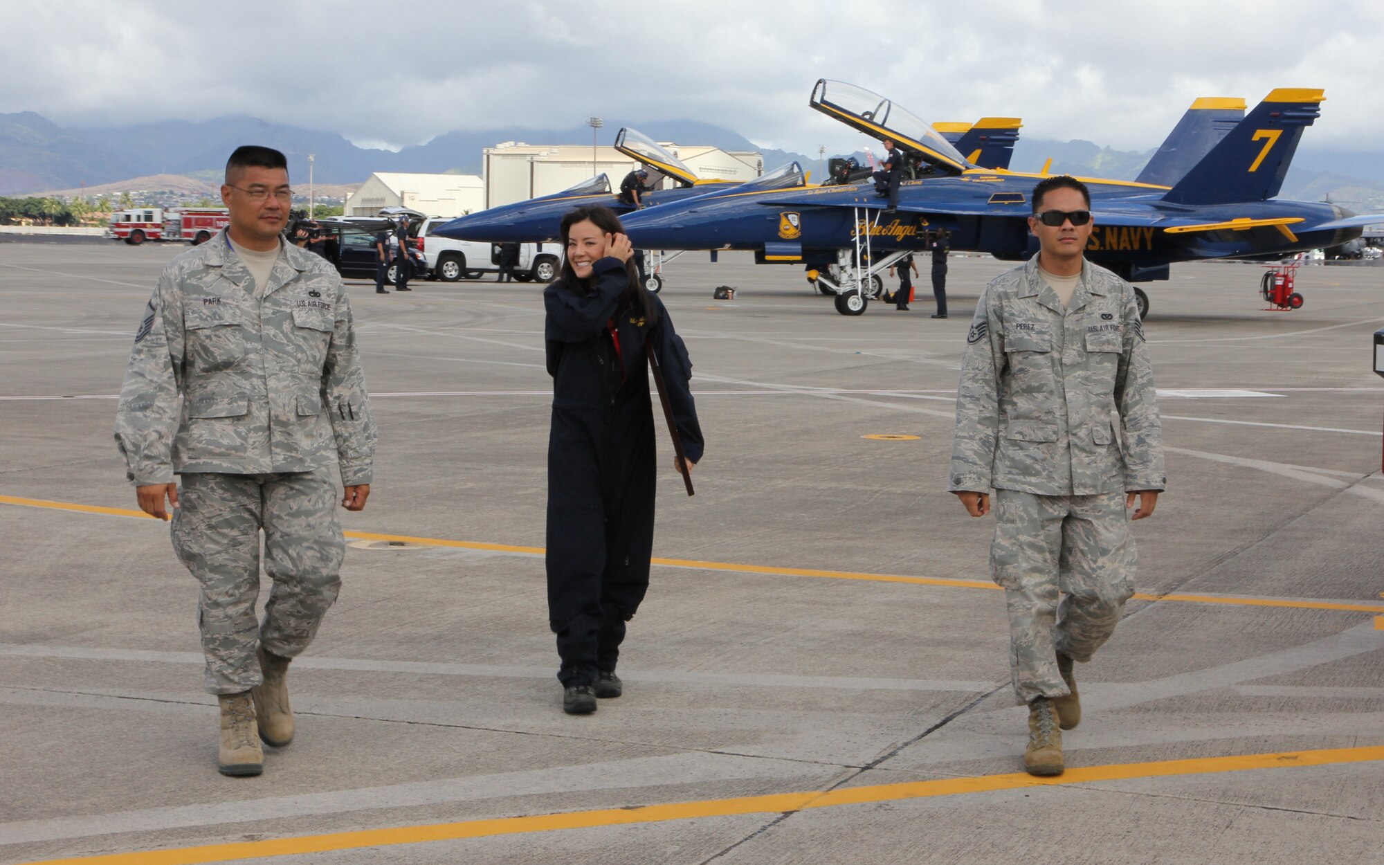 Master Sgt. Glenn Park, left, an air transportation craftsman with the 48th Aerial Port Squadron, and Staff Sgt. Lyle Perez, right, an electrician with the 624th Civil Engineering Squadron, escort Lara Yamada, center, a reporter for KITV-Honolulu, off the flight line after her incentive flight in a Blue Angels’ F/A-18 Hornet, Joint Base Pearl Harbor-Hickam, Hawaii, Sept. 26, 2014. Members of the 624th Regional Support Group provided media escort for special events leading up to the “Wings Over the Pacific” air show held at Hickam Field, Hawaii, Sept. 27-28, 2014. (U.S. Air Force photo by Tech. Sgt. Phyllis Keith)