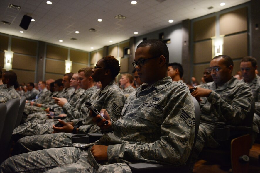 U.S. Air Force Airmen view their smartphones during a wing commander’s call Sept. 30, 2014, at Dyess Air Force Base, Texas. Through the use of smartphones, participants were able to submit answers to live polls that were used by the commander during his brief to address issues and concerns in near-real-time. (U.S. Air Force photo by Airman 1st Class Kedesha Pennant/Released)