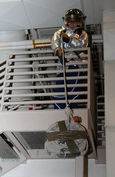 Second Lt. Cory Degroot, 28th Civil Engineer Squadron programmer, pulls a water hose over a railing during the firefighter challenge at Ellsworth Air Force Base, S.D., Oct. 3, 2014. Ten teams competed in a variety of modified activities firefighters routinely perform when responding to emergency situations. (U.S. Air Force photo by Senior Airman Hailey R. Staker/Released)   