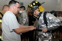 Staff Sgt. Kyle Bailey, 28th Civil Engineer Squadron firefighter, tightens the straps of an oxygen tank on 2nd. Lt. Cory Degroot, 28th CES programmer, before competing in the firefighter challenge at Ellsworth Air Force Base, S.D., Oct. 3, 2014. The challenge included obstacles such as a hose and dummy drag, hose carry, ladder climb and hose pull as part of the kick-off for Fire Prevention Week, which begins Oct. 6. (U.S. Air Force photo by Senior Airman Hailey R. Staker/Released) 