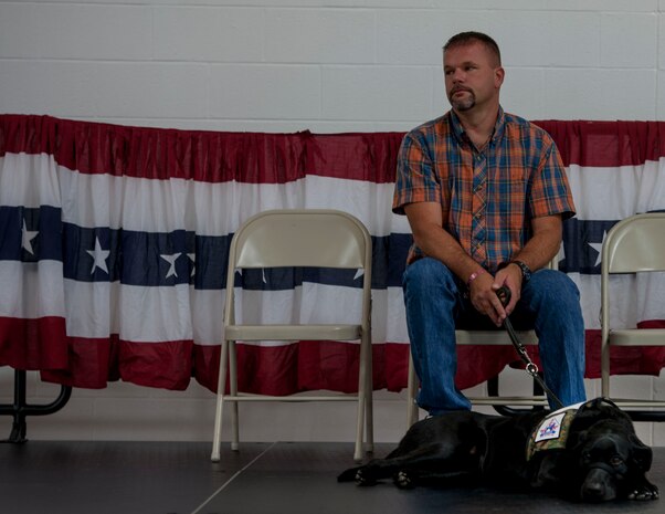 Sean Knapp, a U.S. Army veteran, sits with Bosor, a 19-month old Labrador retriever, during a dog placement ceremony Oct. 2, 2014, at the Naval Consolidated Brig Charleston on Joint Base Charleston, S.C. Bosor was trained by inmates at the NCBC in partnership with Canines For Service, Inc.  (U.S. Air Force photo / Senior Airman Tom Brading)