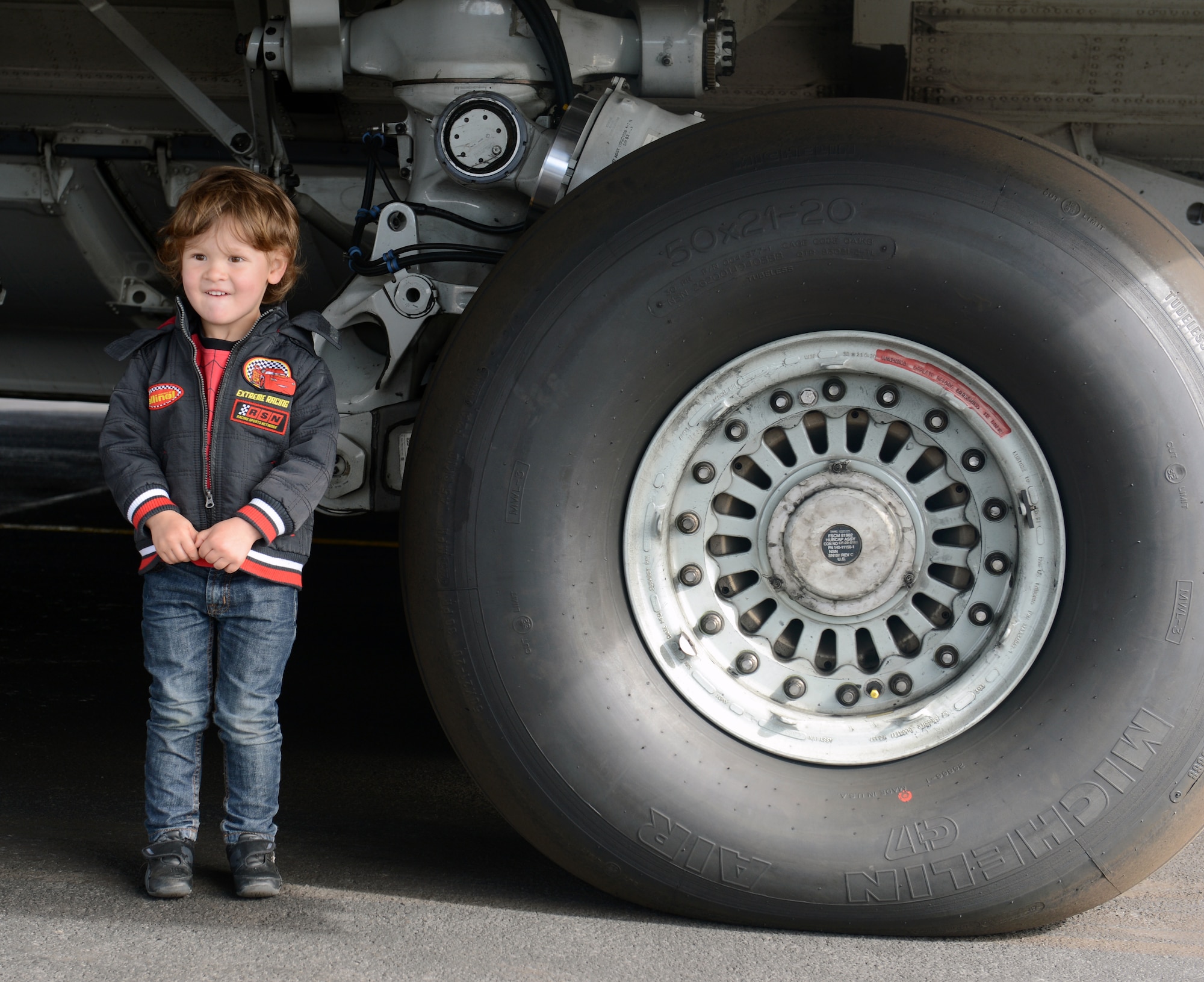 A young New Zealand boy poses for a photo beside the tire of a C-17 Globemaster III, Oct. 5th, 2014, as part of the U.S. Antarctic Program Day for IceFest 2014 at Christchurch, New Zealand. Children had a chance to walk around the aircraft and ask questions of the 62nd and 446th Airlift Wing Airmen who participated in this year’s event. (U.S. Air Force photo/Master Sgt. Todd Wivell)