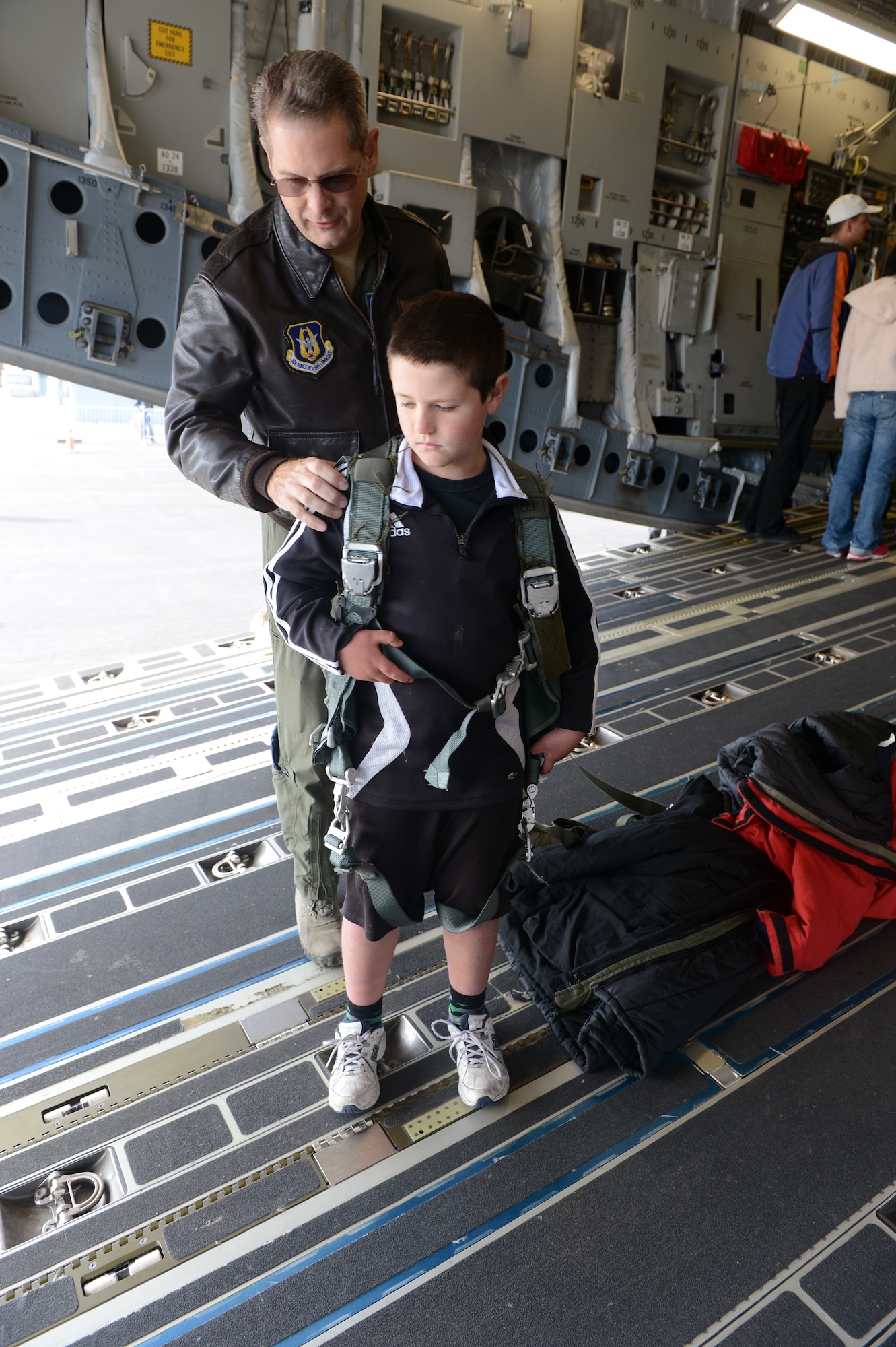 Chief Master Sgt. Jim Masura, 304th Expeditionary Airlift Squadron superintendent and 97th Airlift Squadron resource manager, helps a young New Zealander try on a parachute rigging on the C-17 Globemaster III, Oct. 5th, 2014, as part of the U.S. Antarctic Program Day for IceFest 2014 at Christchurch, New Zealand. Masura spent the entire day answering questions about the aircraft and visited with the more than 7,000 guests who attended. (U.S. Air Force photo/Master Sgt. Todd Wivell)