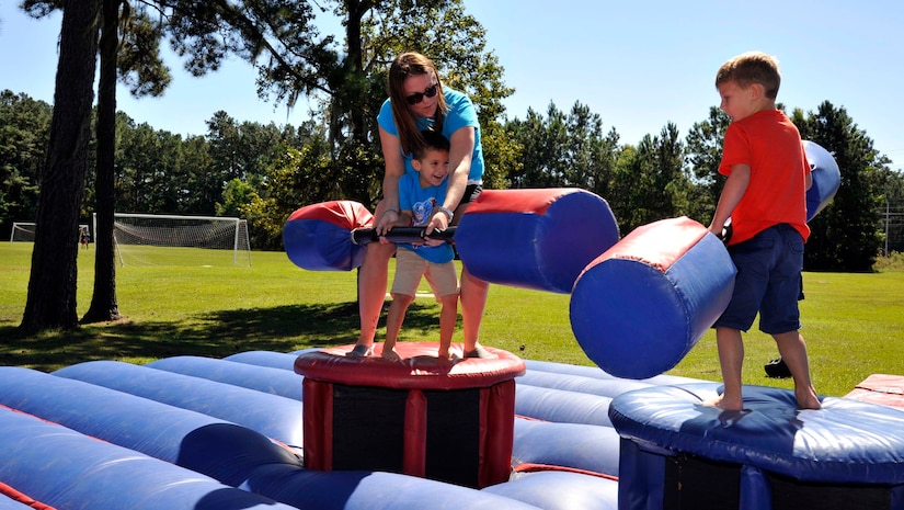 Danette McCracken, helps 3-year old Alex Beutler, in a jousting competition versus 4-year old Mason McCracken, Oct. 4, 2014, at the Joint Base Charleston birthday bash at Locklear Park on JB Charleston, S.C. The picnic included BBQ from the Redbank Club, face painting, corn hole, jousting and a live bluegrass band. (U.S. Air Force photo/Staff Sgt. Renae Pittman)