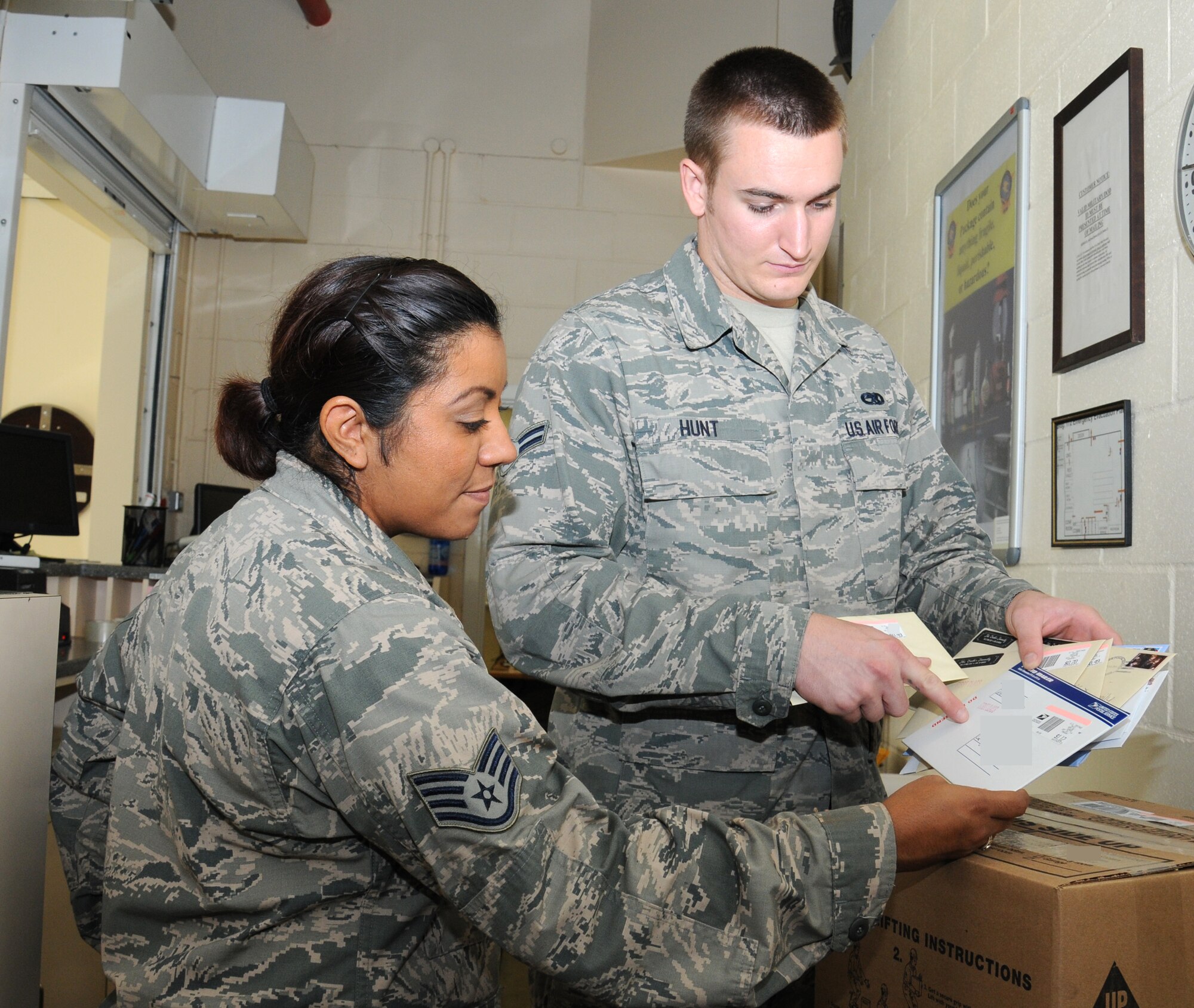 U.S. Air Force Staff Sgt. Rebecca Pecina, left, 100th Communications Squadron NCO in charge of mail processing from San Antonio, speaks with U.S. Air Force Airman 1st Class Kyle Hunt, 100th CS postal clerk from Mission Viejo, Calif., regarding a mail delivery Oct. 1, 2014, on RAF Mildenhall, England. The post office is starting to prepare for the holiday season. (U.S. Air Force photo/Gina Randall/Released)