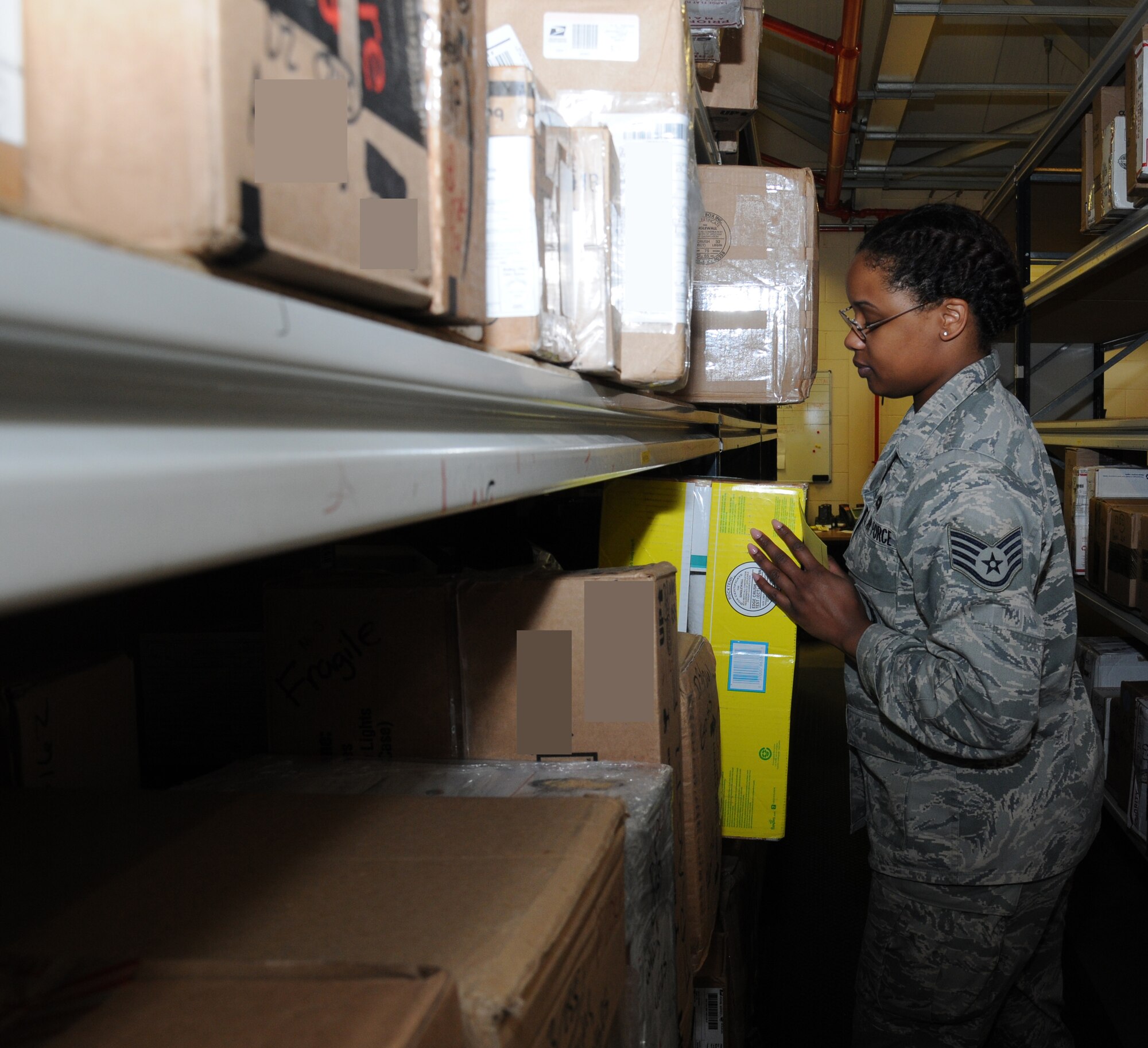 U.S. Air Force Staff Sgt. Candice Griffin, 100th Communications Squadron postal clerk from Baltimore, places a box on a shelf Oct. 1, 2014, on RAF Mildenhall, England. The RAF Mildenhall Post Office has 124 storage units to help process 600,000 pounds of mail annually. (U.S. Air Force photo/Gina Randall/Released)