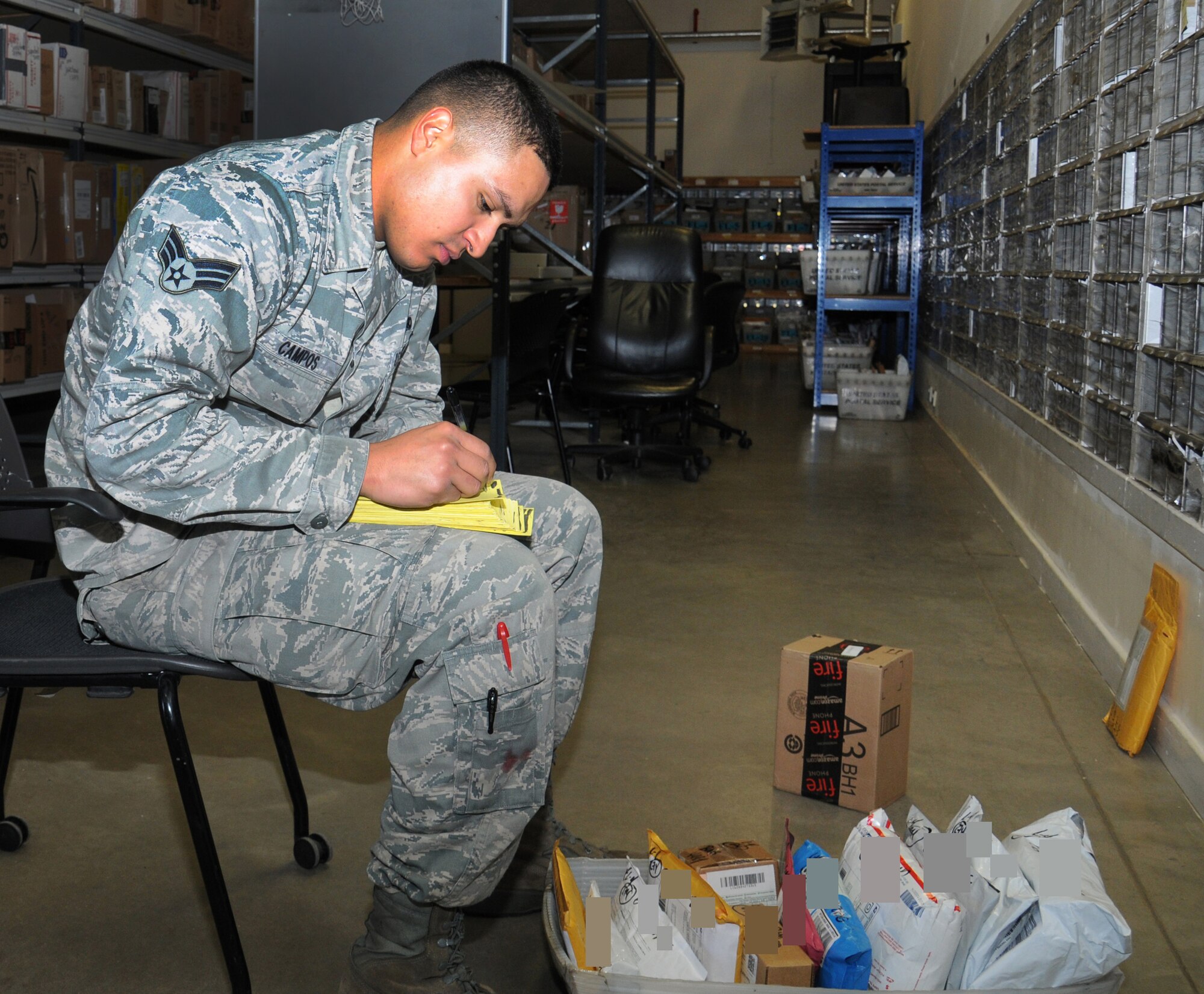 U.S. Air Force Senior Airman Oscar Campos Ortiz, 100th Communications Squadron postal clerk from Dallas, writes up parcel notifications Oct. 1, 2014, on RAF Mildenhall, England. The RAF Mildenhall Post Office processes approximately 137,000 packages annually. (U.S. Air Force photo/Gina Randall/Released)