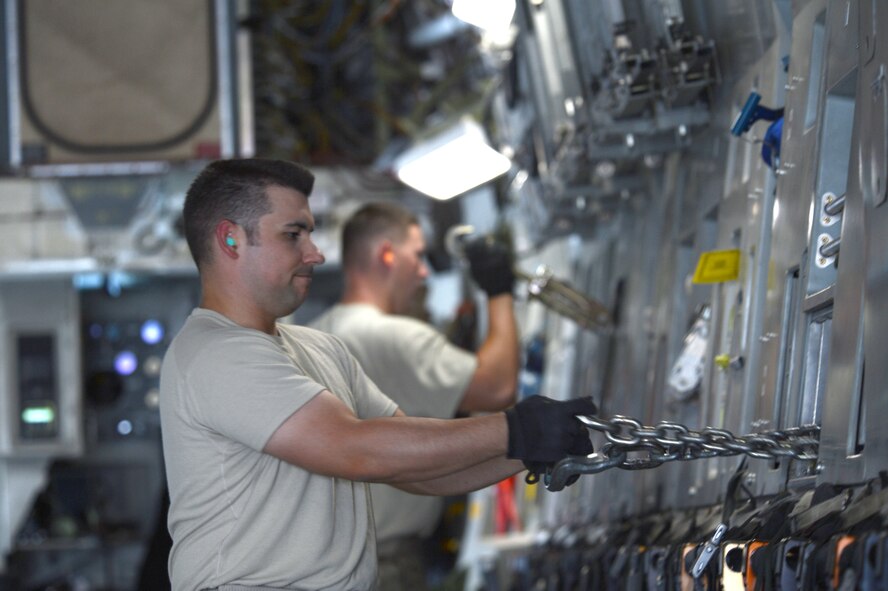 U.S. Air Force Staff Sgt. Reuben Montes, an air transportation journeyman assigned to the 455th Expeditionary Aerial Port Squadron Detachment 1, pulls chains from a storage rack aboard a Joint Base Charleston C-17 Globemaster III in preparation of loading and securing a Heavy Expanded Mobility Tactical Truck while at Mazar-e Sharif, Afghanistan June 24, 2014. Montes, a native of Worthington, Ohio, is deployed from the 375th Logistics Readiness Squadron, Scott Air Force Base, Ill. (U.S. Air Force photo by Master Sgt. Cohen A. Young/Released)  