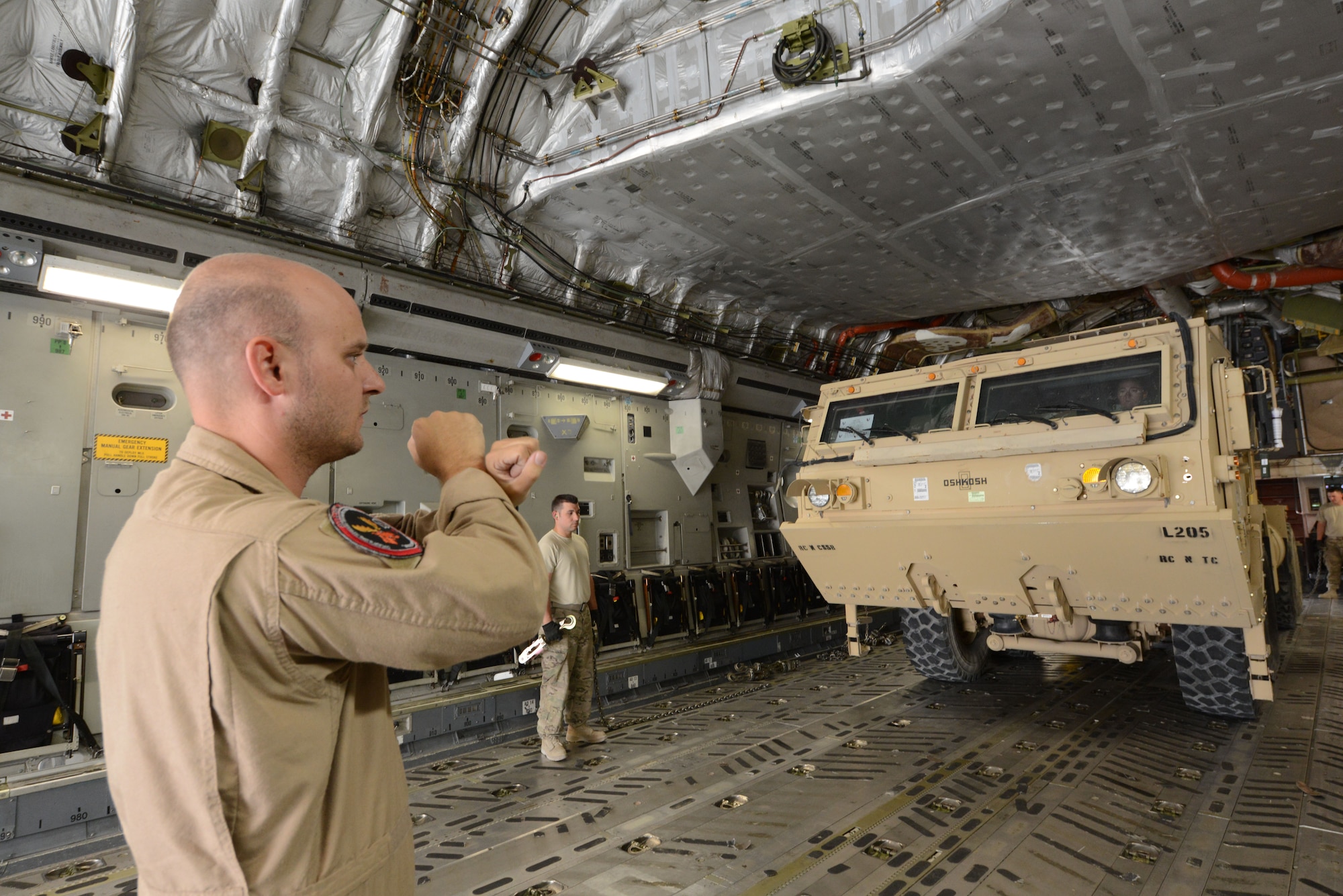 U.S. Air Force Staff Sgt. Doug Wattier, a loadmaster assigned to 816th Expeditionary Airlift Squadron, Detachment 2, signals the driver of a Heavy Expanded Mobility Tactical Truck to stop after backing onto a C-17 Globemaster III while at Mazar-e Sharif, Afghanistan June 24, 2014. Loadmasters are responsible for ensuring where and how vehicles, pallets and equipment are positioned on aircraft. Wattier, a native of Jacksonville, N.C. is deployed from the 317th Airlift Squadron at Joint Base Charleston, S.C. (U.S. Air Force photo by Master Sgt. Cohen A. Young/Released)  