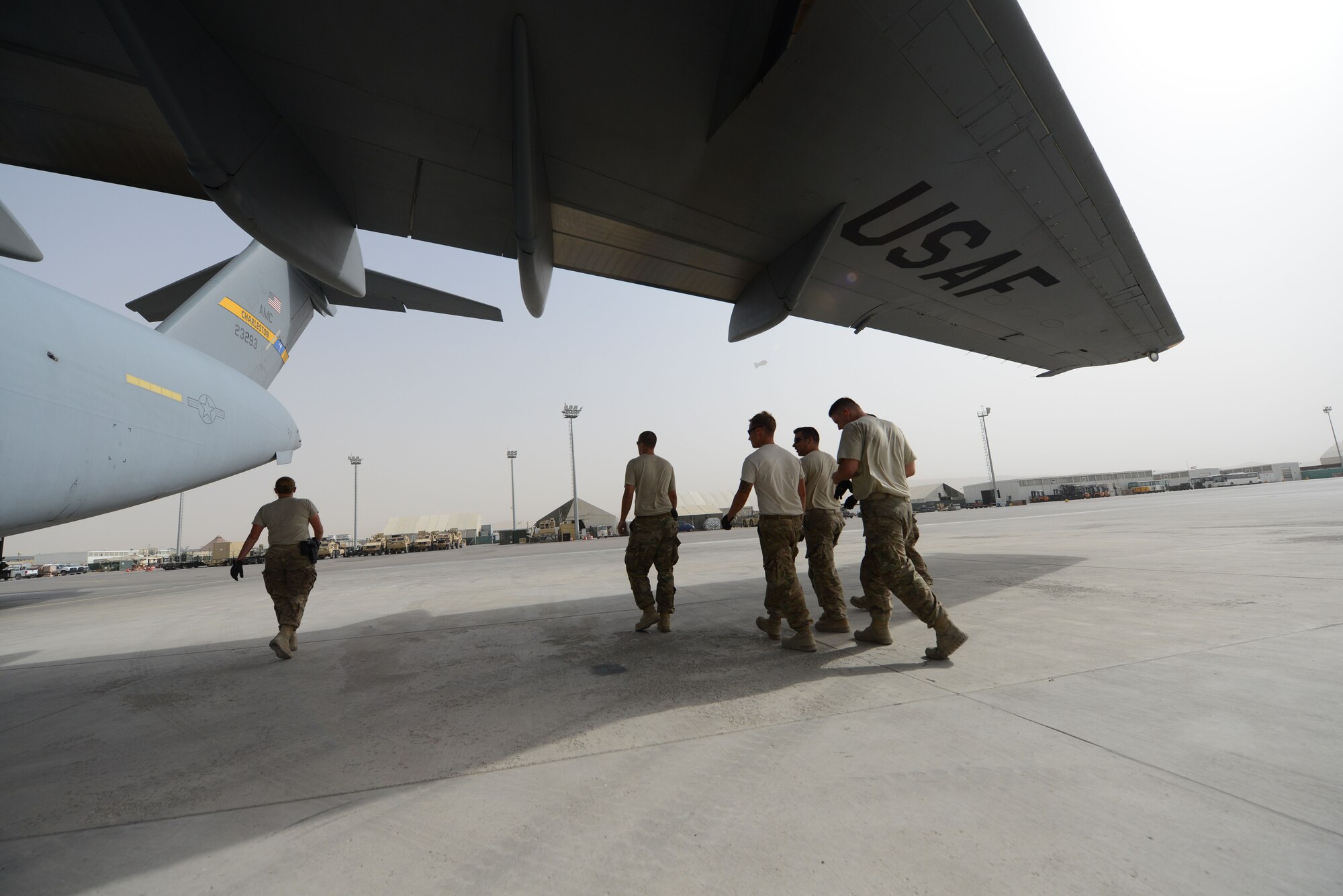 Airmen assigned to the 455th Expeditionary Aerial Port Squadron Detachment 1, walk back to the Air Terminal Operations Center after loading two Heavy Expanded Mobility Tactical Trucks onto a C-17 Globemaster III at Mazar-e Sharif, Afghanistan June 24, 2014. As part of the retrograde mission, EAPS Det 1 is responsible for inspecting and loading cargo and vehicles leaving Mazar-e Sharif.