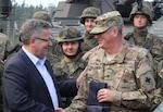 Col. Mark Jackson, commanding officer of the 33rd Infantry Brigade Combat Team, shakes hands with Bronislaw Komorowski, the president of Poland, in Orzysz, Poland, Oct. 2, 2014.  Jackson presented Komorowski a plaque on behalf of the 33rd IBCT.