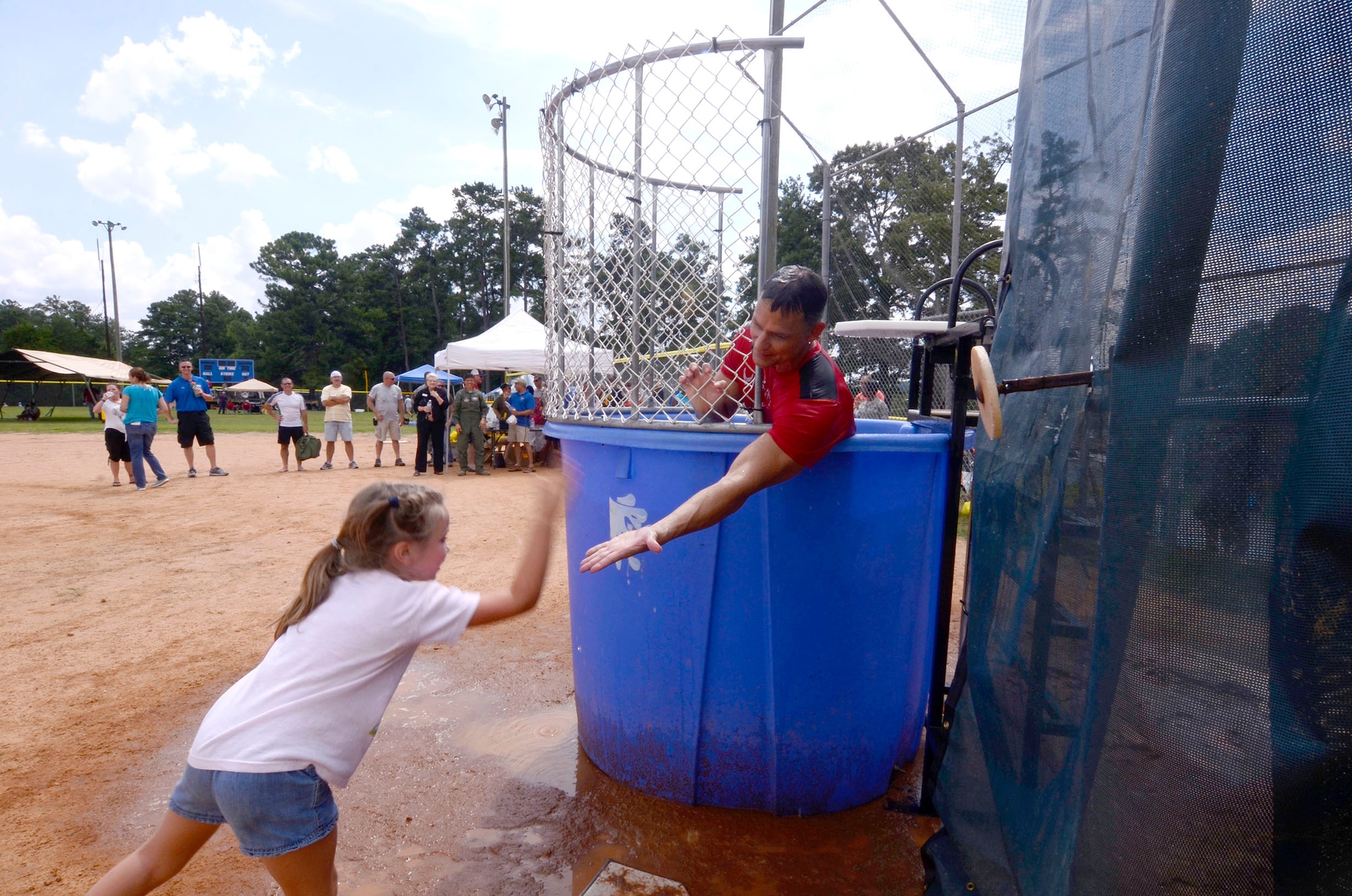 Col. Brett Clark, 94th Airlift Wing commander, congratulates a wing family member for dunking him during the Annual Wing Family Day Sept. 6, 2014 at the Dobbins Lakeside Recreation Area. Attendees also enjoyed music, food, automobile displays, exhibits, vendors, auctions, jumpy castles, face painting, a medival display, pet adoption, raffles, and Atlanta Falcons ticket giveaways. (U.S. Air Force photo/Don Peek)