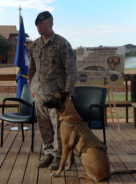 U.S. Air Force Staff Sgt. Sean Davis, 7th Security Forces Squadron, military working dog (MWD) handler, stands at attention next to his MWD, FForde Sept. 25, 2014 at Dyess Air Force Base, Texas. Upon retirement, FForde will become part of Davis’ family. (U.S. Air Force photo by Airman 1st Class Autumn Velez/Released)