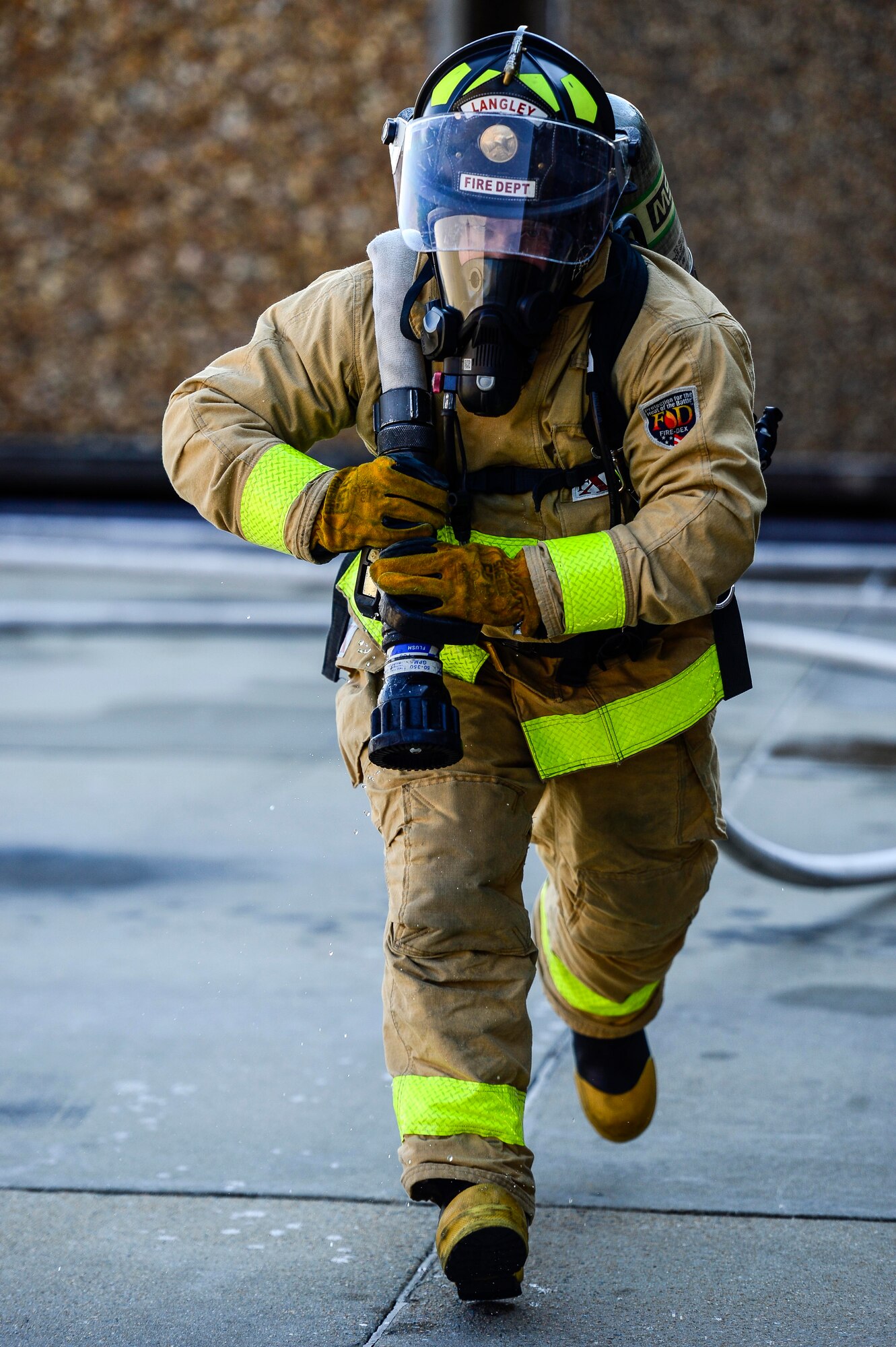 U.S. Air Force Airman 1st Class Colton Peer, 633rd Civil Engineer Squadron firefighter, sprints with a hose during a firefighter challenge at Langley Air Force Base, Va., Oct. 1, 2014. The hose pull, along with ladder climbs, a keiser sled and a dummy drag, were among the 13 essential tasks the firefighters were required to perform. (U.S. Air Force photo by Senior Airman Kayla Newman/Released)