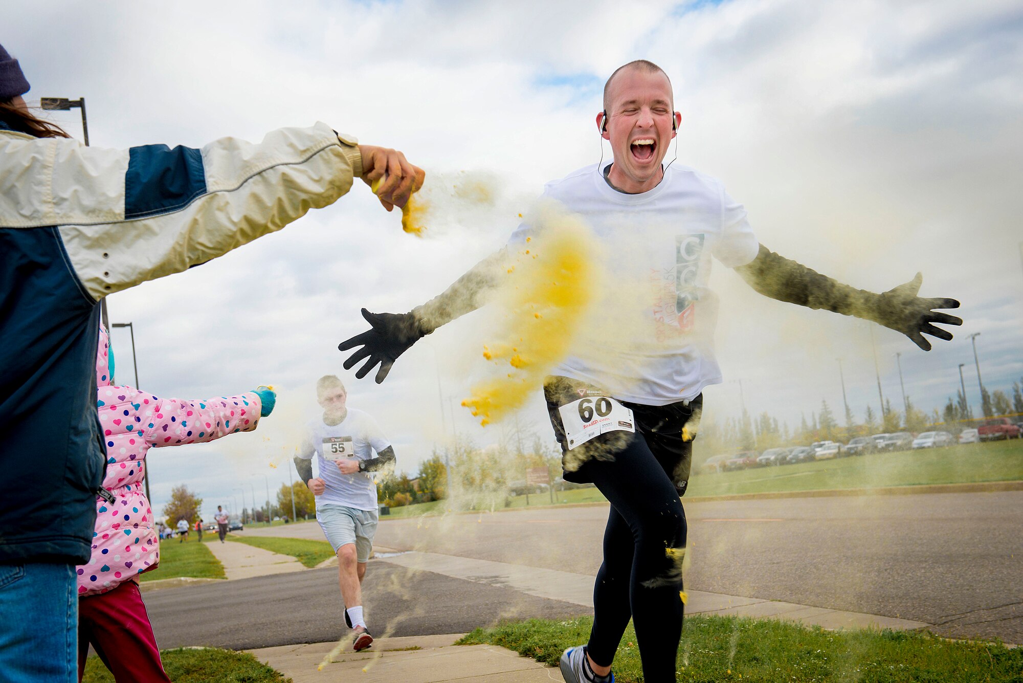 Staff Sgt. Joshua Hull, NCO in charge of Minot Air Force Base honor guard, is hit with yellow powder during the Color Me Safe 5K on Minot Air Force Base, N.D., Oct. 3, 2014.Participants ran the 5K route to raise awareness for domestic violence, and along the way were doused by different colored powders.  (U.S. Air Force photo/Airman 1st Class Sahara L. Fales)