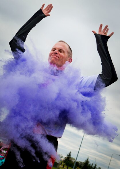 Col. Michael Lutton, 91st Missile Wing commander, runs through a cloud of purple powder on Minot Air Force Base, N.D., Oct. 3, 2014. The Family Advocacy Clinic partnered with the McAdoo Fitness Center to host the Color Me Safe 5K to raise awareness for domestic violence.  (U.S. Air Force photo/Airman 1st Class Sahara L. Fales)