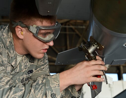 U.S. Air Force Airman 1st Class Aaron Shive, 20th Aircraft Maintenance Squadron weapons load crew member, with the Gamblers Aircraft Maintenance Unit, fastens an MK-82 slick missile to an F-16CM Fighting Falcon during a weapons load crew competition at Shaw Air Force Base, S.C., Oct. 3, 2014. The crews are evaluated on how they load weapons, their dress and appearance per AFI 36-2903, and their job knowledge through the load competition, an inspection, and a 10-question written test. (U.S. Air Force photo by Senior Airman Tabatha Zarrella/Released)