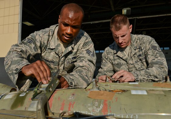 U.S. Air Force Senior Airman Stephen Caseman, 20th Aircraft Maintenance Squadron weapons load crew member, and Staff Sgt. Randy Therriault, 20th AMXS weapons load crew chief, both with the Gamblers Aircraft Maintenance Unit, unstrap MK-82 slick missiles during a load crew competition at Shaw Air Force Base, S.C., Oct. 3, 2014. The purpose of the competition was to evaluate the weapons load crews capabilities and see who is the best weapons load crew. (U.S. Air Force photo by Senior Airman Tabatha Zarrella/Released)