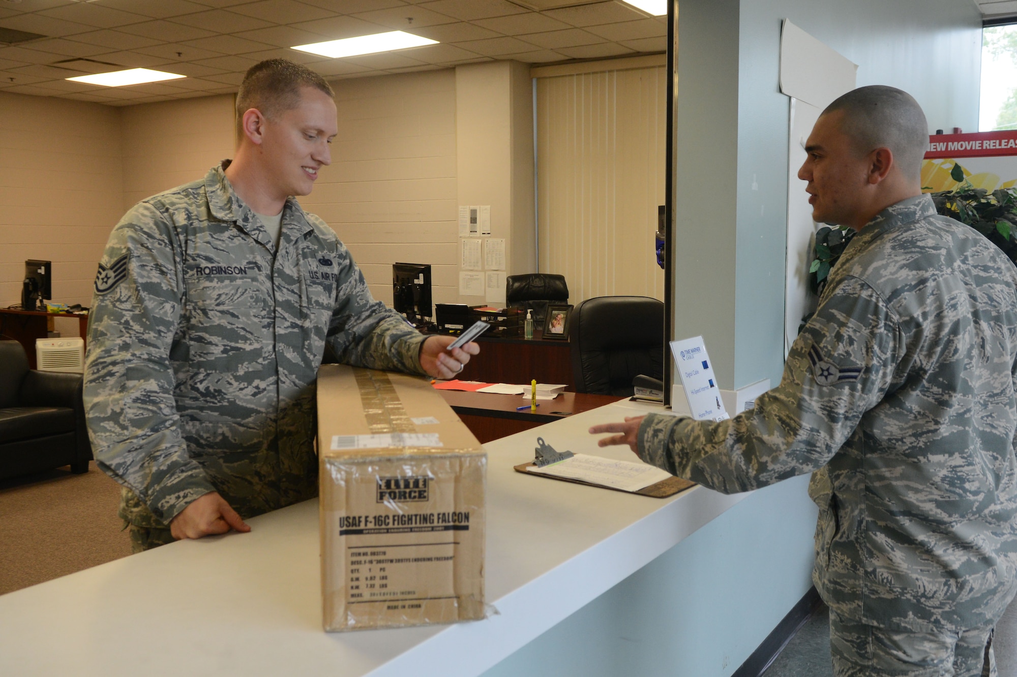 U.S. Air Force Staff Sgt. Matthew Robinson, 20th Civil Engineer Squadron Airman dormitory leader, verifies the identification of Airman 1st Class Andrew Zambrano, 609th Air Operations Center Detachment 1 command control battle management operator at Shaw Air Force Base, S.C., Oct. 3, 2014. Dorm management has taken over the mail room duties for FedEx items of dorm residents. (U.S. Air Force photo by Senior Airman Ashley L. Gardner/Released)