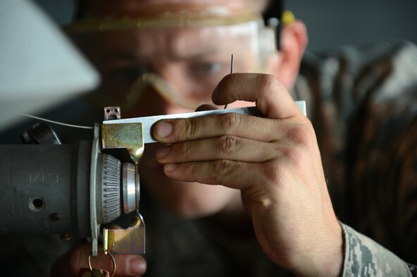U.S. Air Force Senior Airman Richard Hamrick, 20th Equipment Maintenance Squadron weapons load crew member, measures an arming wire after attaching an MK-82 slick missile onto an F-16CM Fighting Falcon at Shaw Air Force Base, S.C., Oct. 3, 2014. Hamrick measured and cut the wire to ensure it was 3 inches long. (U.S. Air Force photo by Airman 1st Class Jensen Stidham/Released)