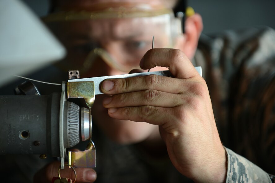 U.S. Air Force Senior Airman Richard Hamrick, 20th Equipment Maintenance Squadron weapons load crew member, measures an arming wire after attaching an MK-82 slick missile onto an F-16CM Fighting Falcon at Shaw Air Force Base, S.C., Oct. 3, 2014. Hamrick measured and cut the wire to ensure it was 3 inches long. (U.S. Air Force photo by Airman 1st Class Jensen Stidham/Released)