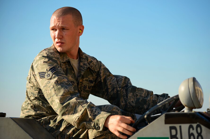 U.S. Air Force Senior Airman Timothy Boehmer, 20th Equipment Maintenance Squadron weapons load crew member, looks over his shoulder while putting a bomb loader in reverse during a weapons load crew competition at Shaw Air Force Base, S.C., Oct. 3, 2014. Bomb loaders are used to transfer and help align heavy munitions before attaching them to an aircraft. (U.S. Air Force photo by Airman 1st Class Jensen Stidham/Released)