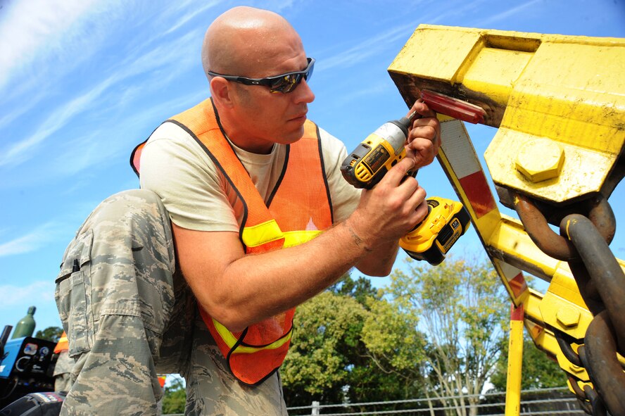 U.S. Air Force Staff Sgt. Travis Bowersock, 20th Civil Engineer Squadron structural journeyman, screws a light onto the barrier at the main gate at Shaw Air Force Base, S.C., Oct. 7, 2014. 20th CES Airmen perform maintenance on the monthly, depending on traffic flow. The routine maintenance includes checking all screws and bolts, removing all water that has leaked into the barrier, and performing a function check to ensure everything is in proper working order. (U.S. Air Force photo by Airman 1st Class Michael Cossaboom/Released)