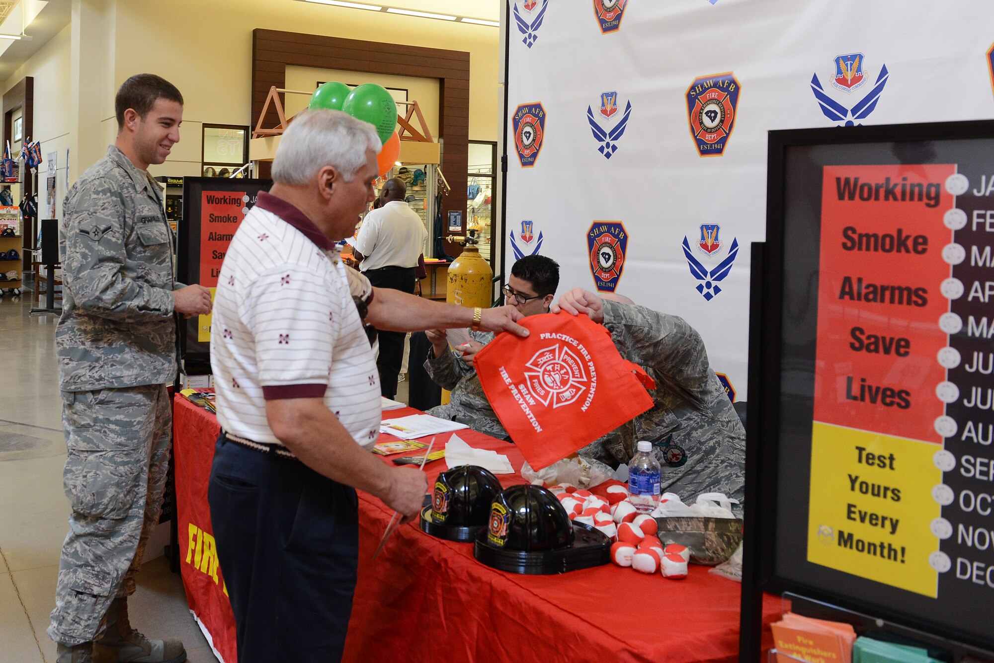 Team Shaw members pick up memorabilia at the Shaw Air Force Base Emergency Services display for a Fire Prevention Week campaign at Shaw AFB, S.C., Oct. 6, 2014. This year’s national campaign highlights “Working smoke alarms save lives: Test yours every month.” (U.S. Air Force photo by Airman 1st Class Diana M. Cossaboom/Released)