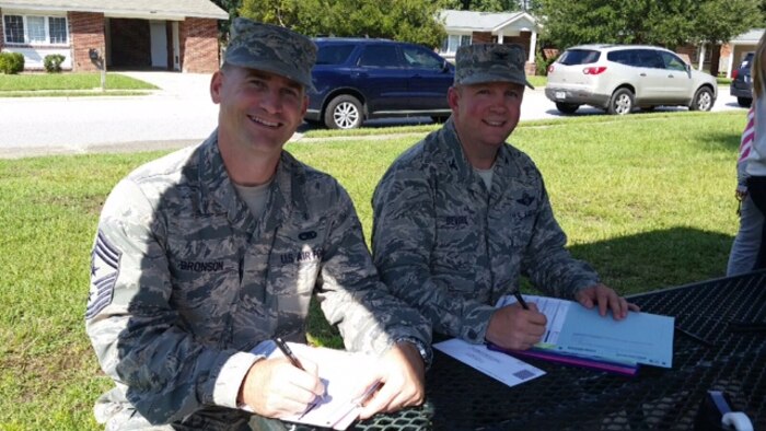 Colonel Jeffrey DeVore, Joint Base Charleston commander, and Chief Master Sgt. Mark Bronson, 628th Air Base Wing command chief, fill out their Forest City Resident Satisfaction Surveys Oct. 1, 2014, at Hunley Park on Joint Base Charleston, S.C. The Resident Satisfaction Survey allows Forest City residents an opportunity to provide feedback to Forest City management. Forest City residents will be able to fill out the survey throughout the month of October. (Courtesy photo)